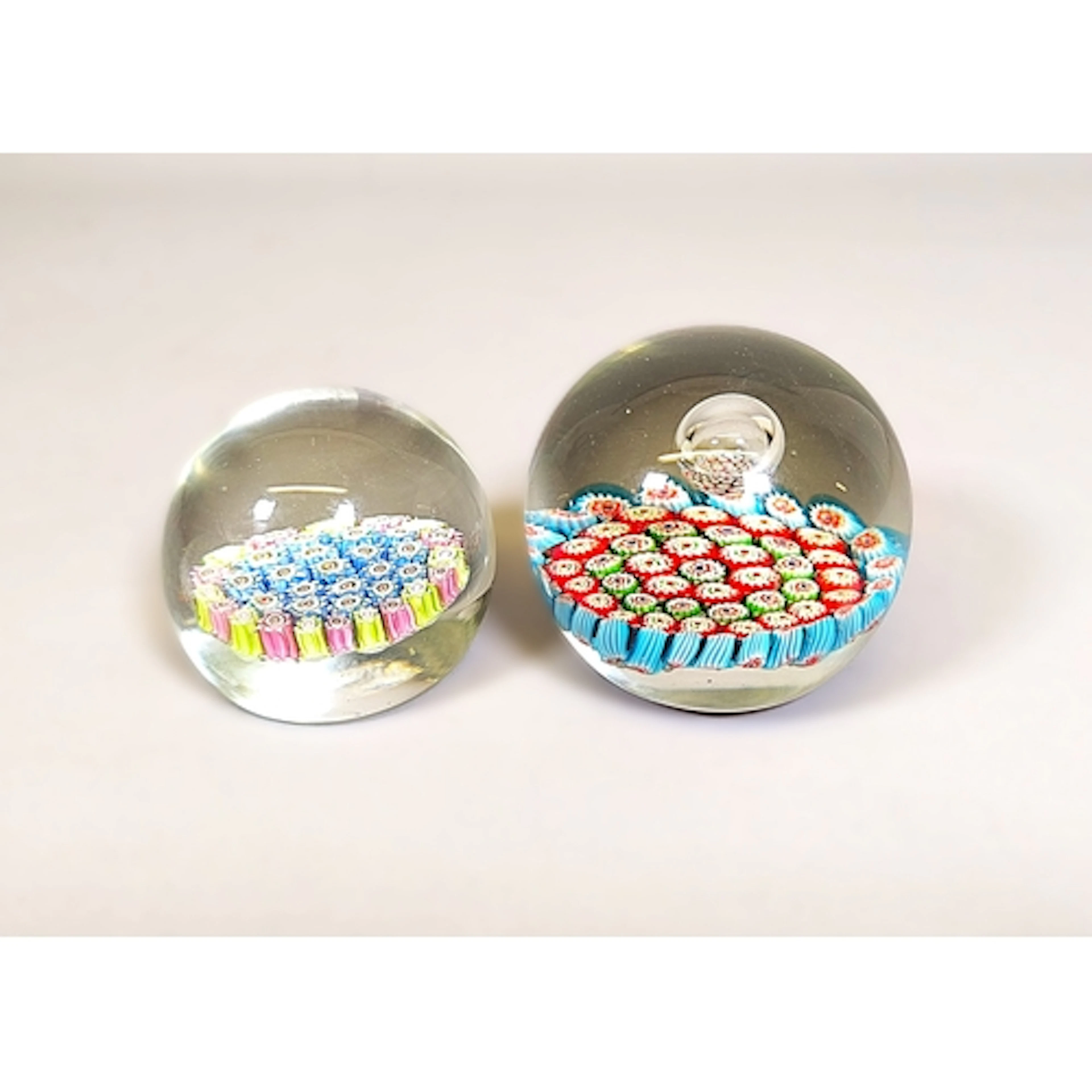 Two vintage millefiori glass paperweights, Designed with mul...