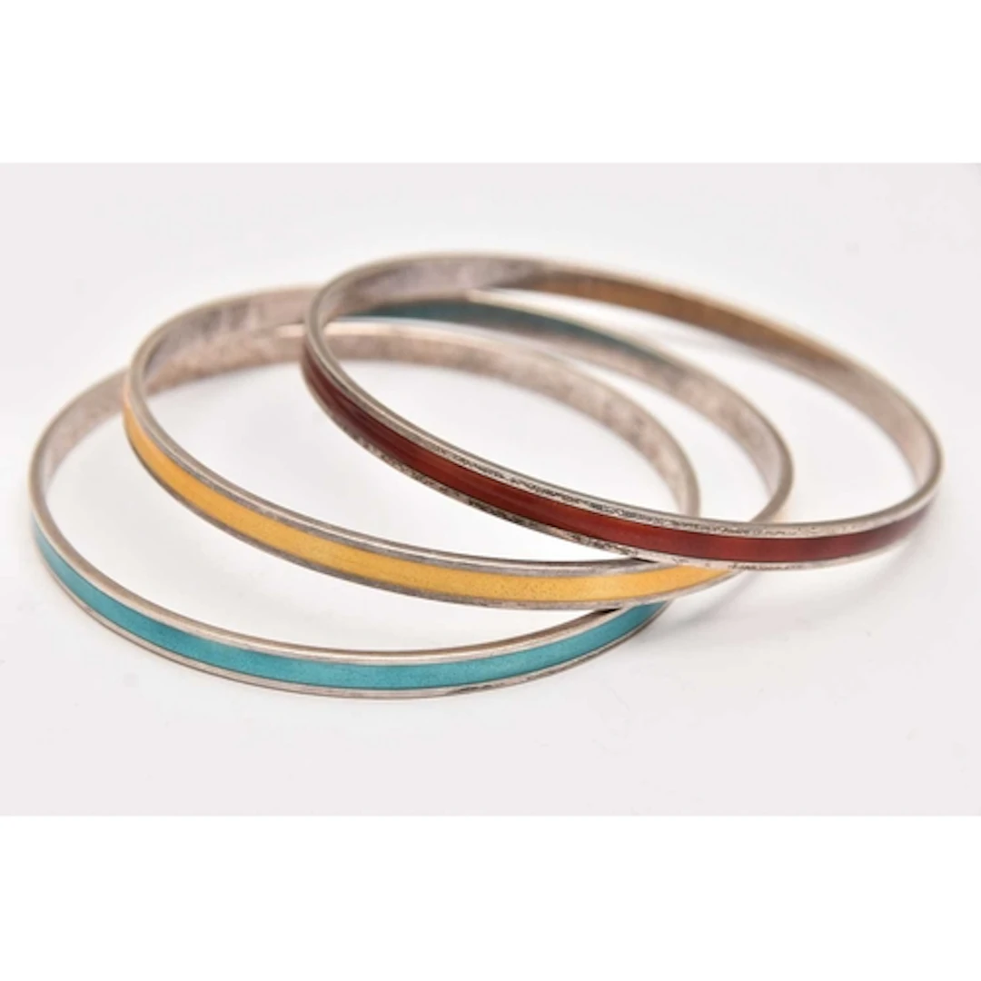 A SET OF THREE 'DAVID-ANDERSEN' WHITE METAL AND ENAMEL BANGL...