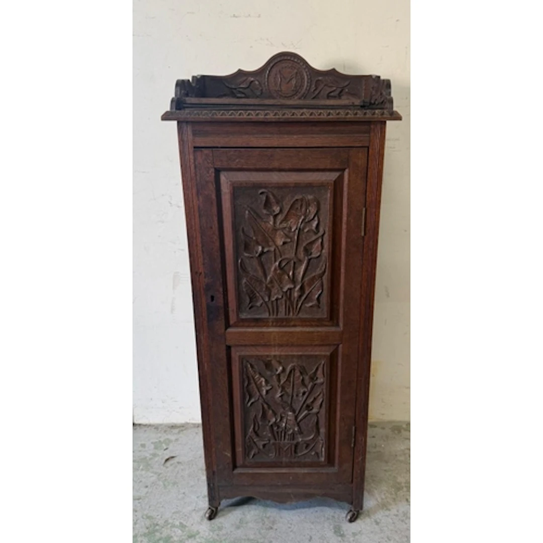 An oak pot cupboard with heavily carved door, sides and a ga...