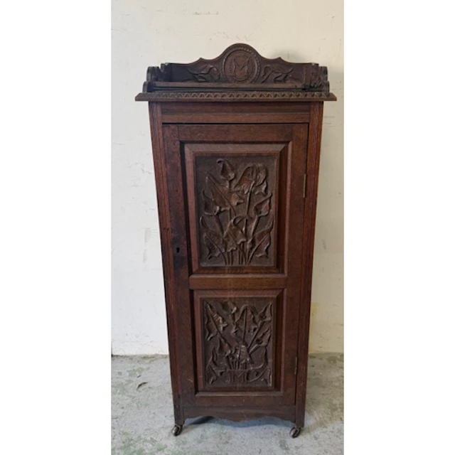 An oak pot cupboard with heavily carved door, sides and a ga...