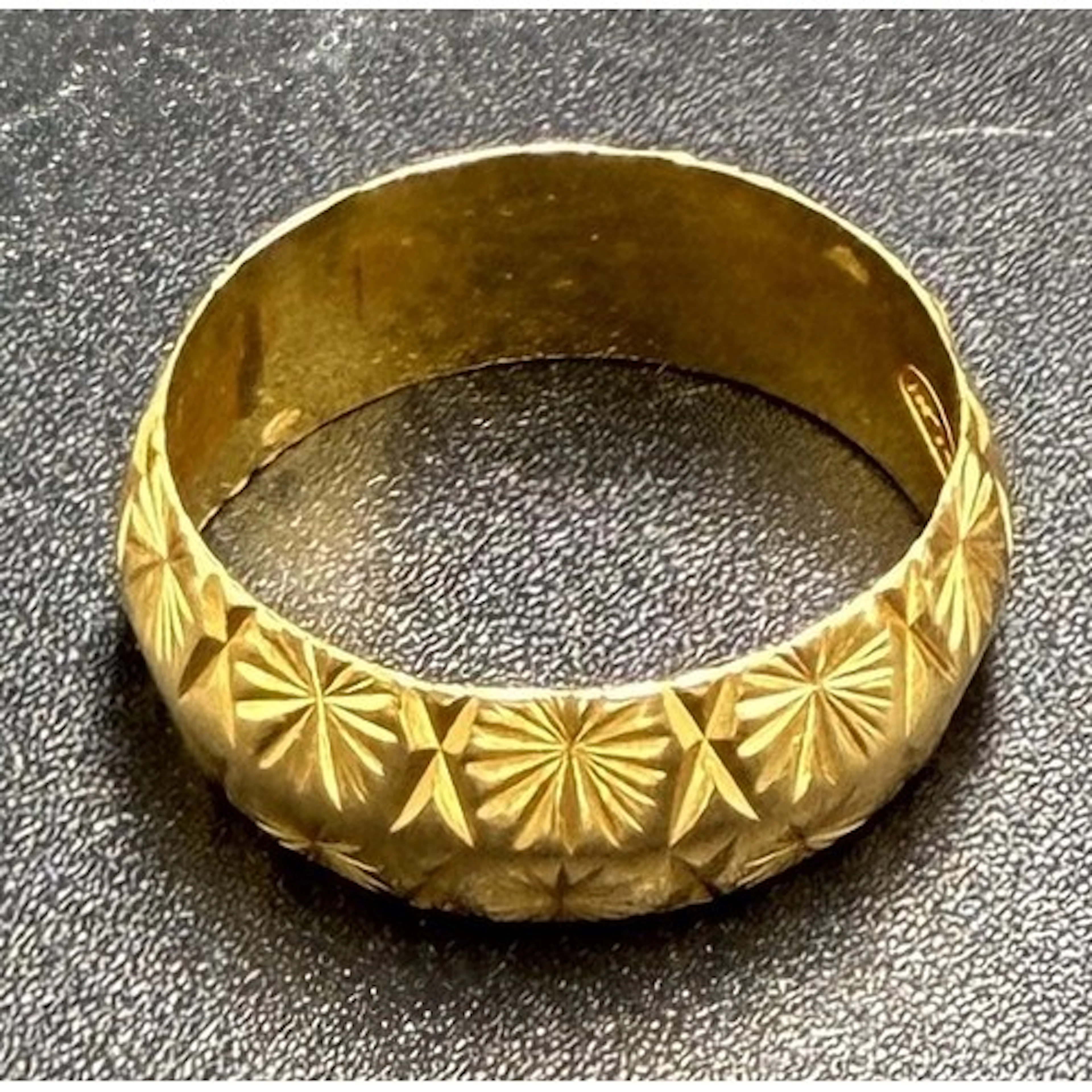 A 22 carat gold wedding band with decorative star pattern. S...
