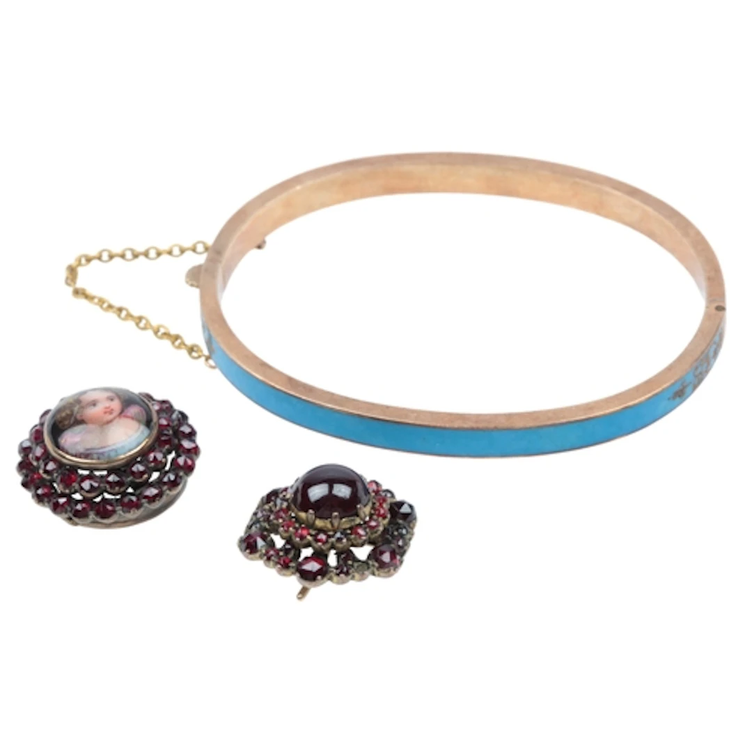 An unmarked gold bangle, of hinged design, applied with blue...