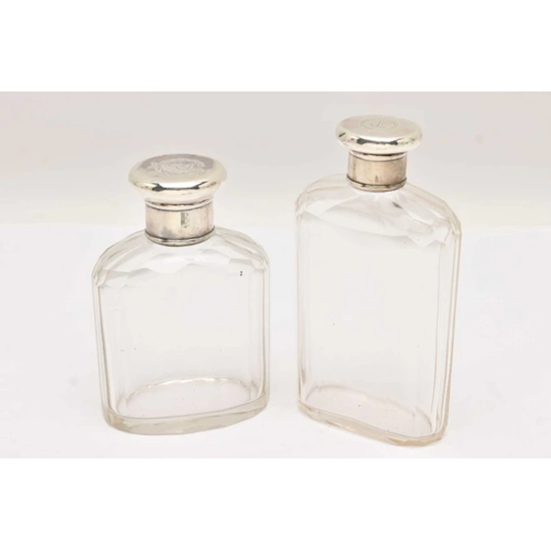 TWO EARLY 20TH CENTURY, GLASS BOTTLES WITH SILVER COVERS, fa...