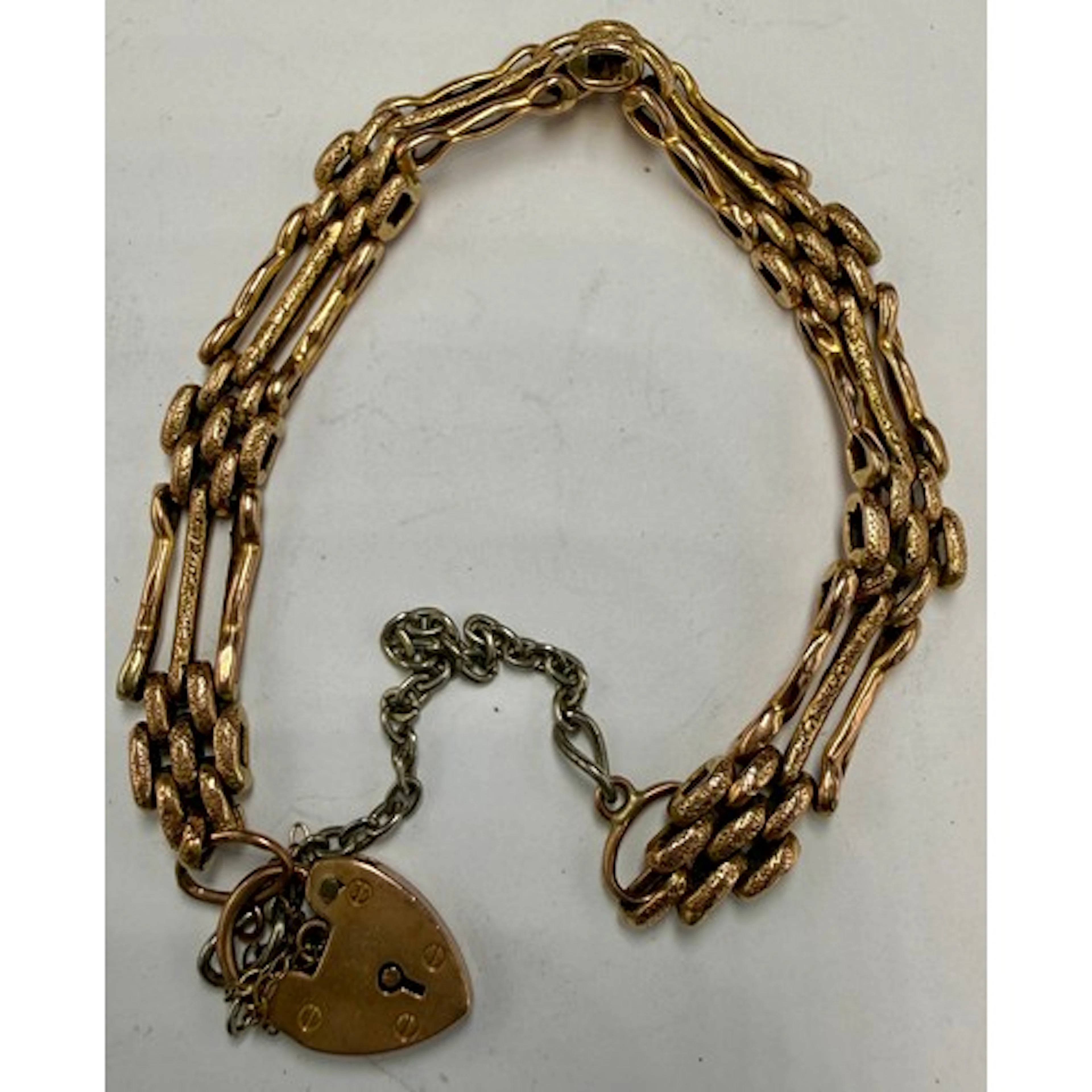 A 9 carat gold gate bracelet with heart shaped padlock faste...