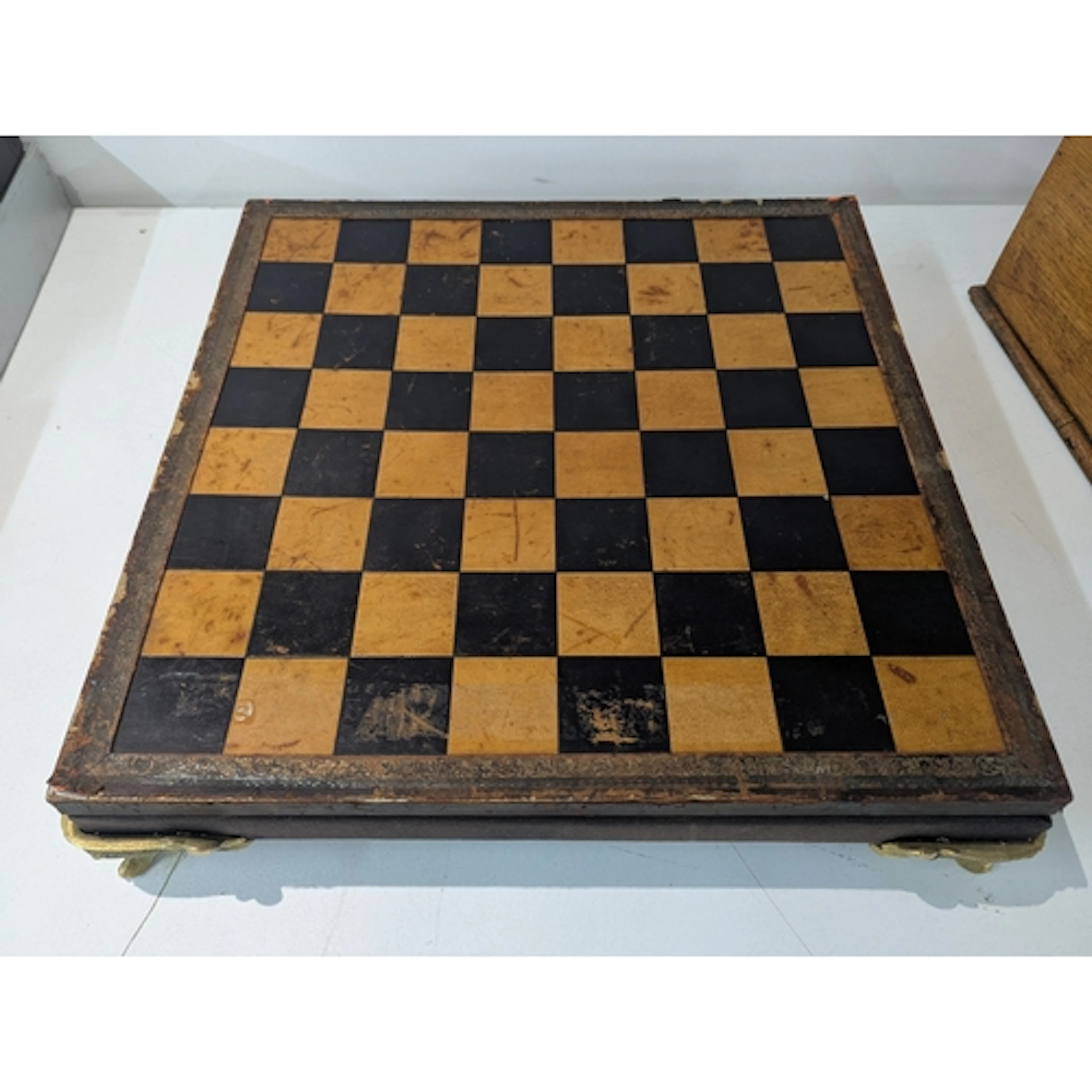 A Leatherette topped chess board, on four ornate brass feet ...