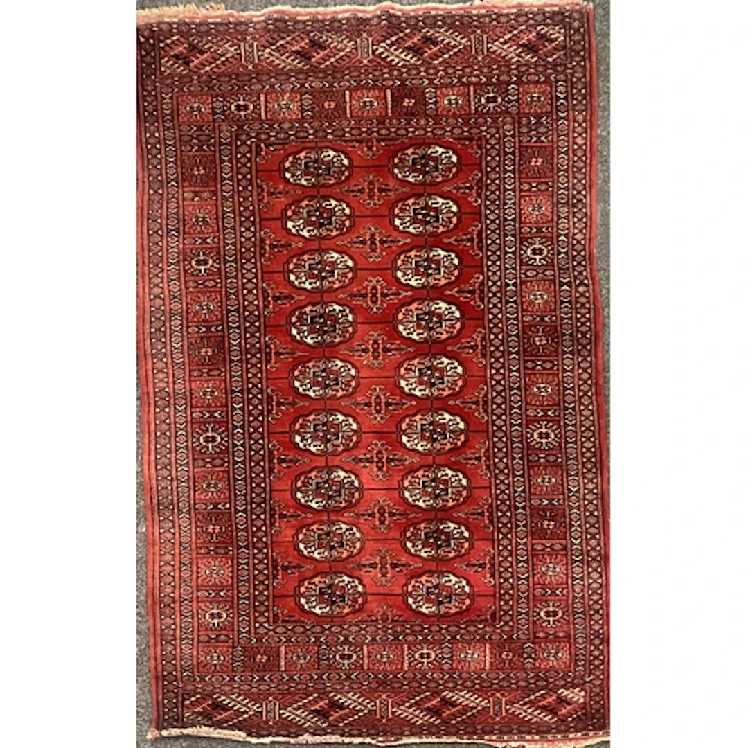 A hand knotted Bokhara rug, deep red field with repeating Gü...