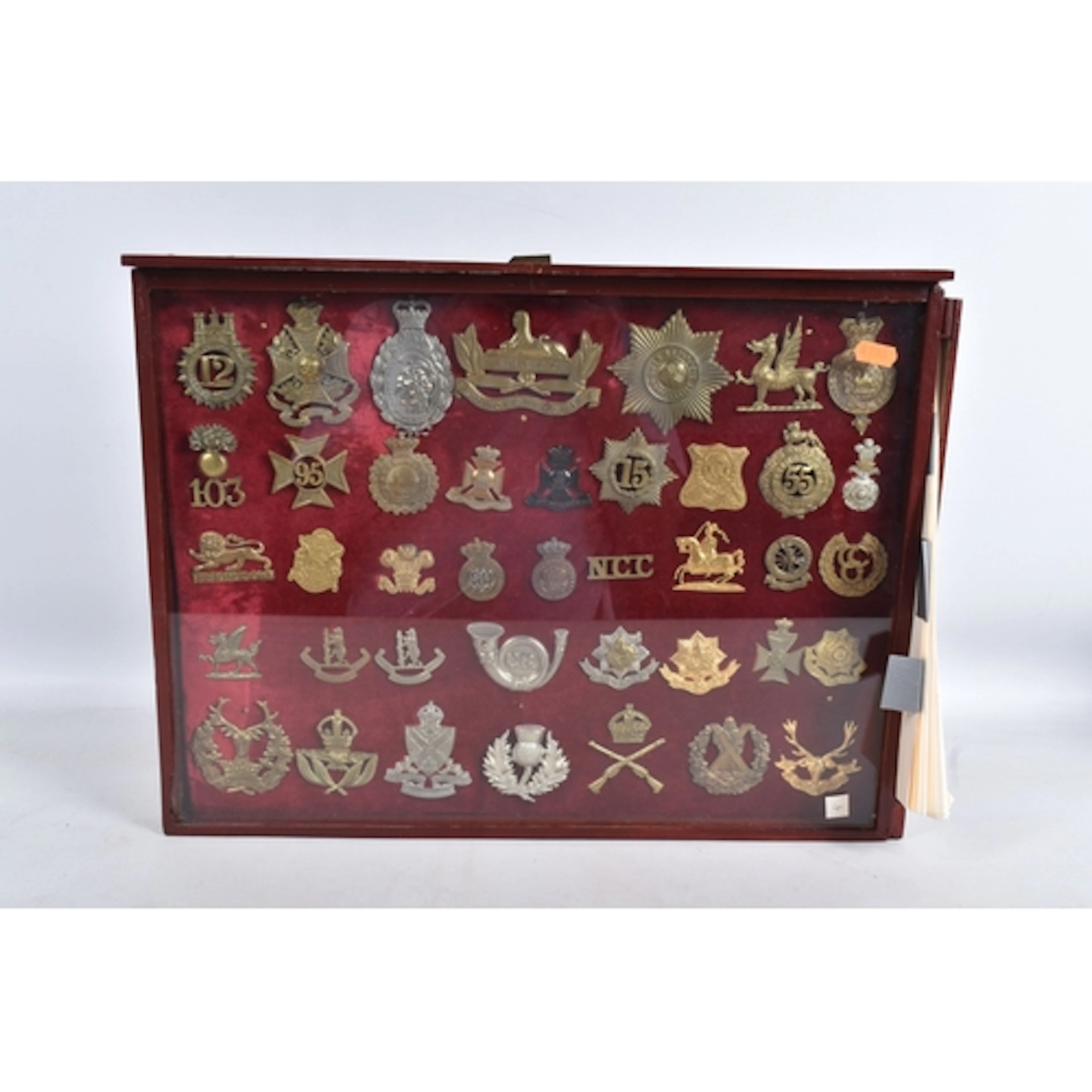 A GLAZED DISPLAY CASE CONTAINING A COLLECTION OF MILITARY BA...