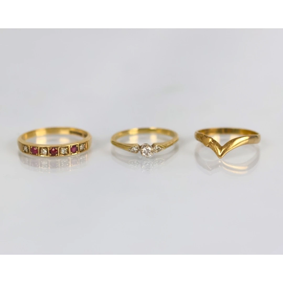 A group of three yellow metal rings, including a ruby and di...