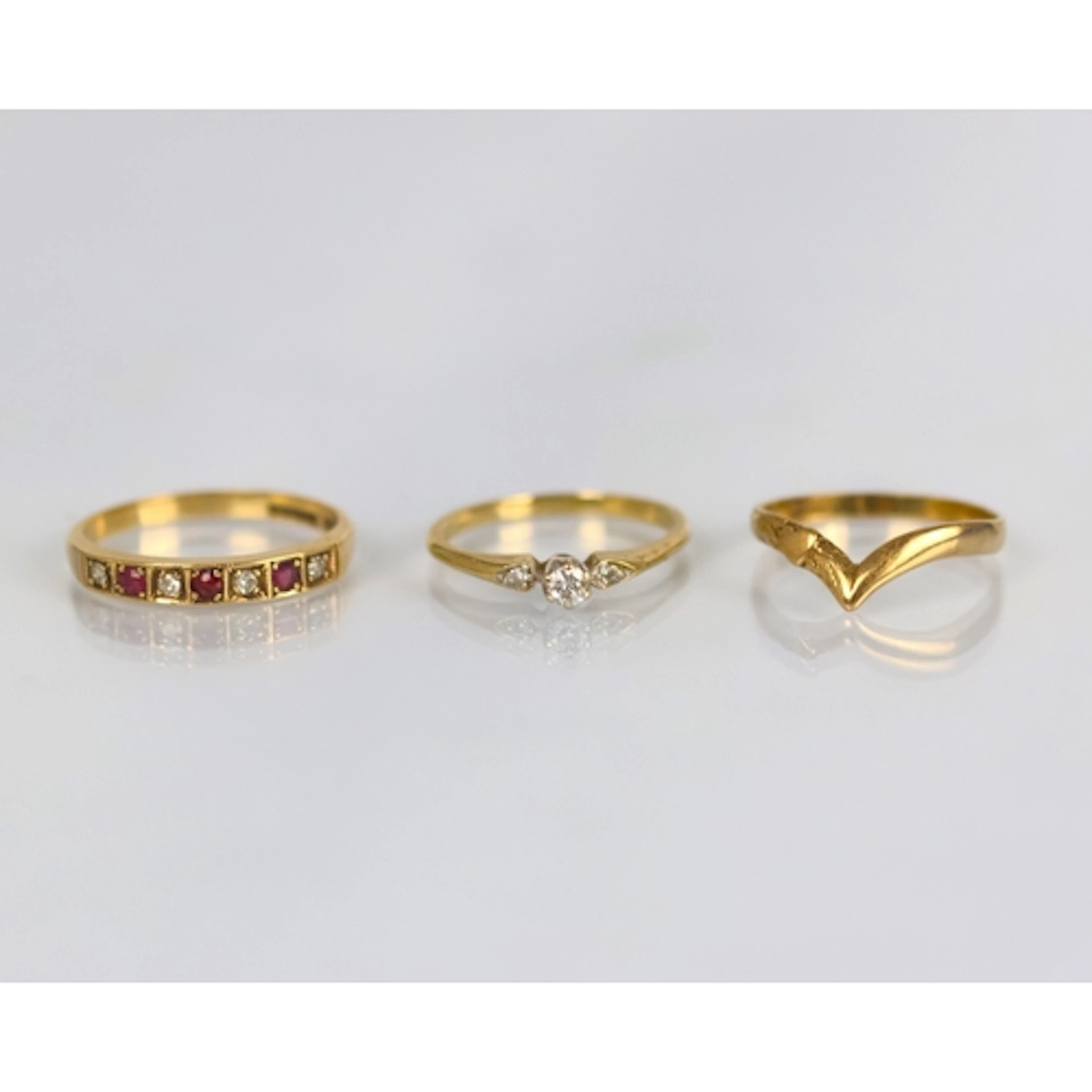 A group of three yellow metal rings, including a ruby and di...
