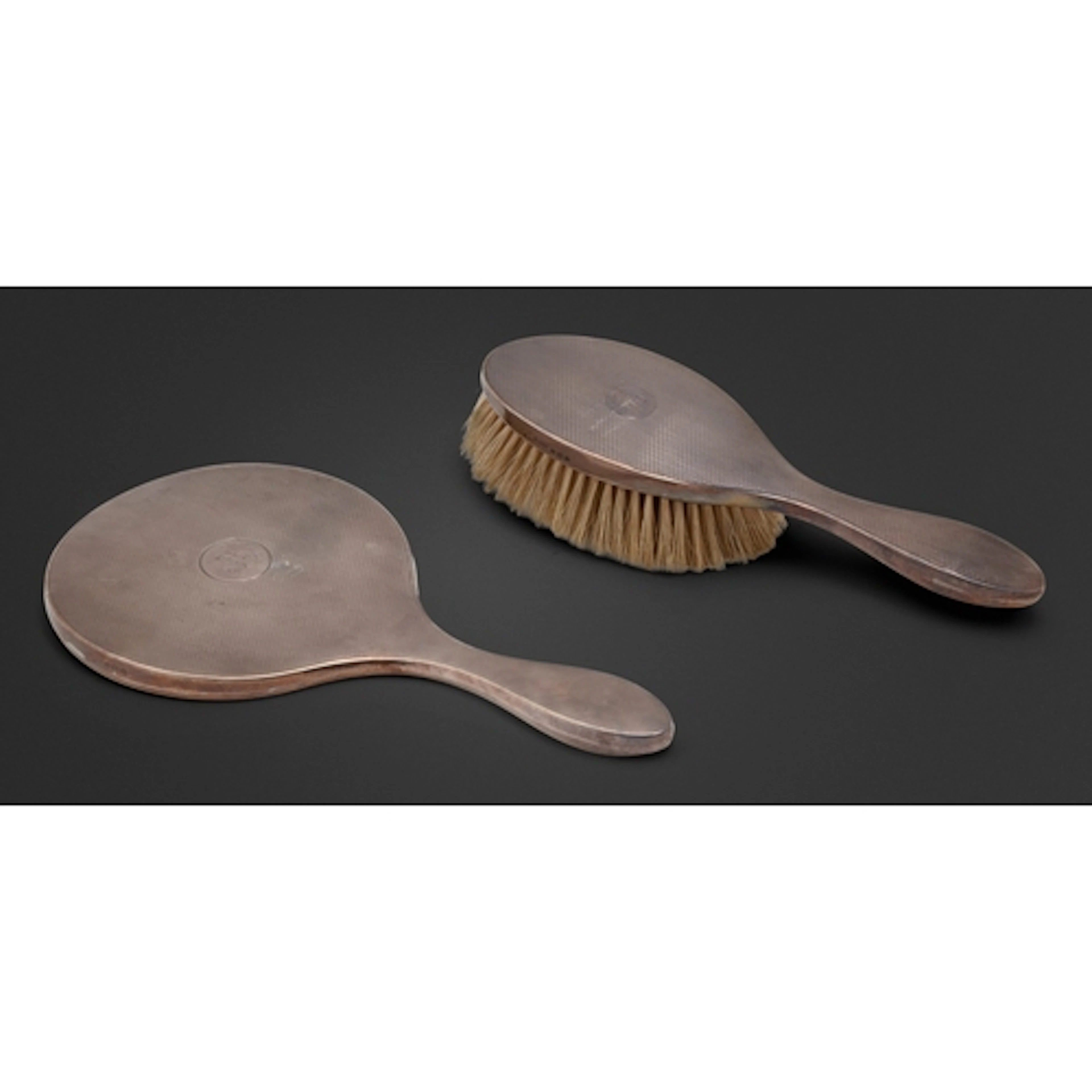 A George V silver hand mirror and hairbrush, engine turned, ...