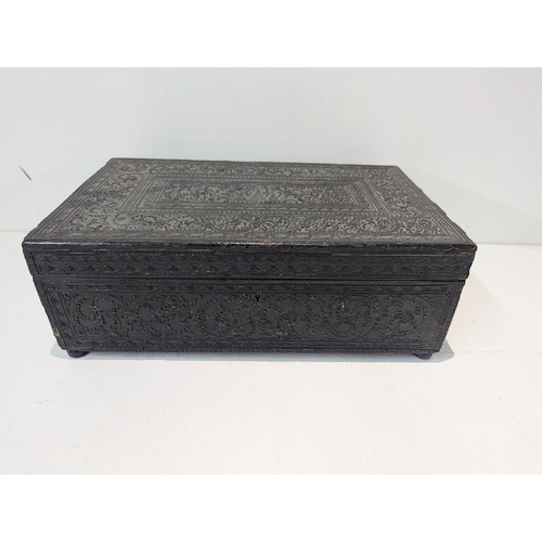 A dark ebonised box featuring intricate, carved floral and g...