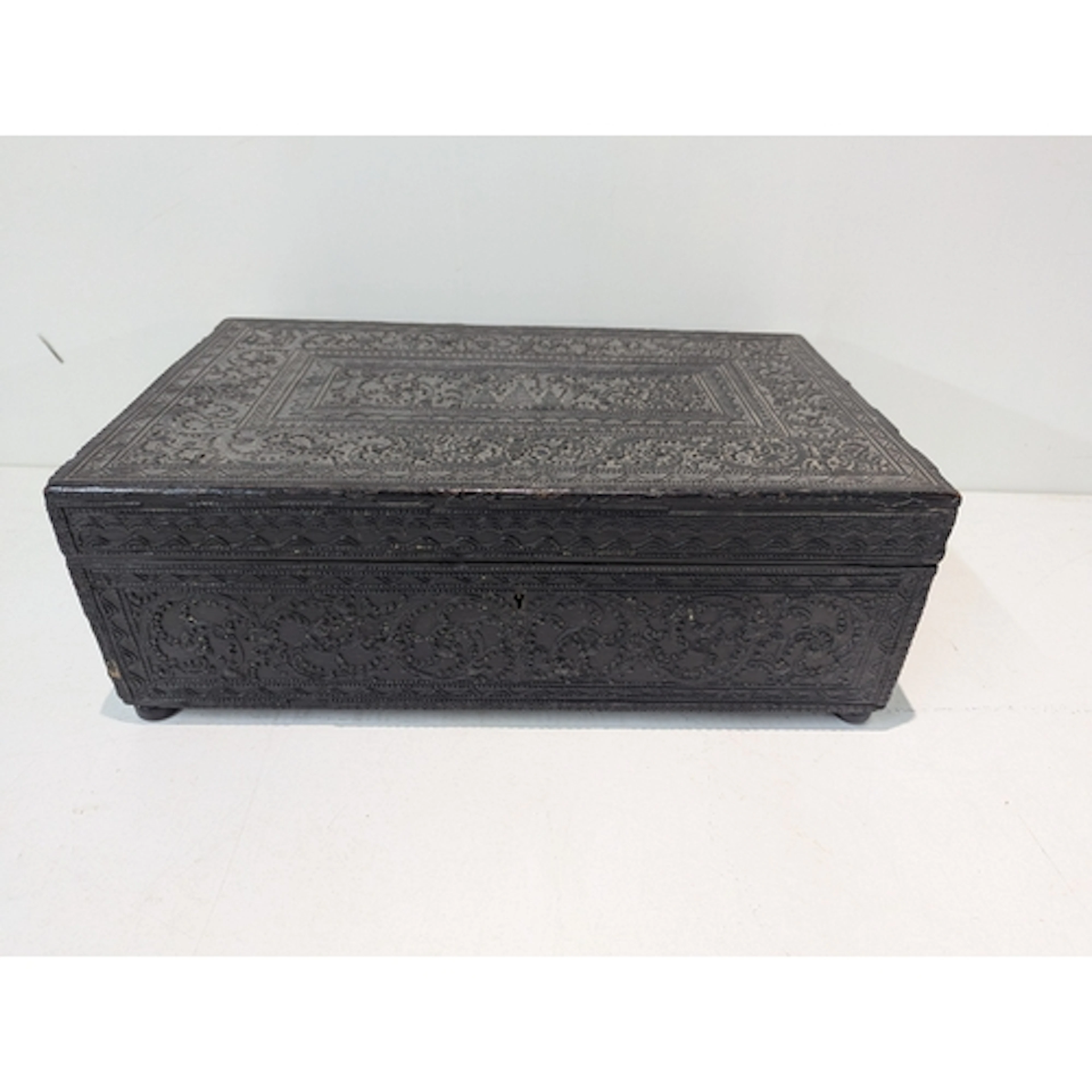 A dark ebonised box featuring intricate, carved floral and g...