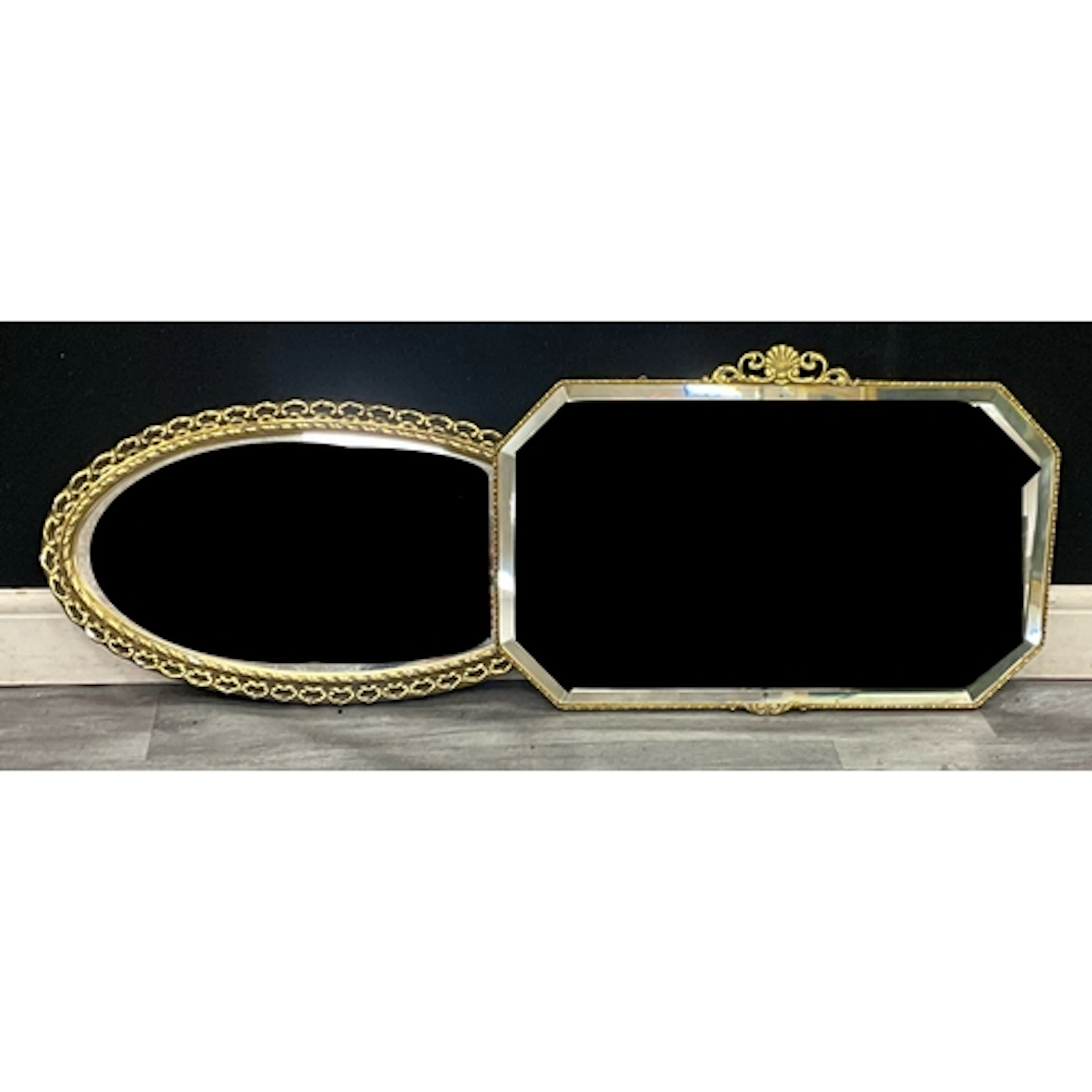 A mid century gilt framed oval mirror with filigree scroll b...