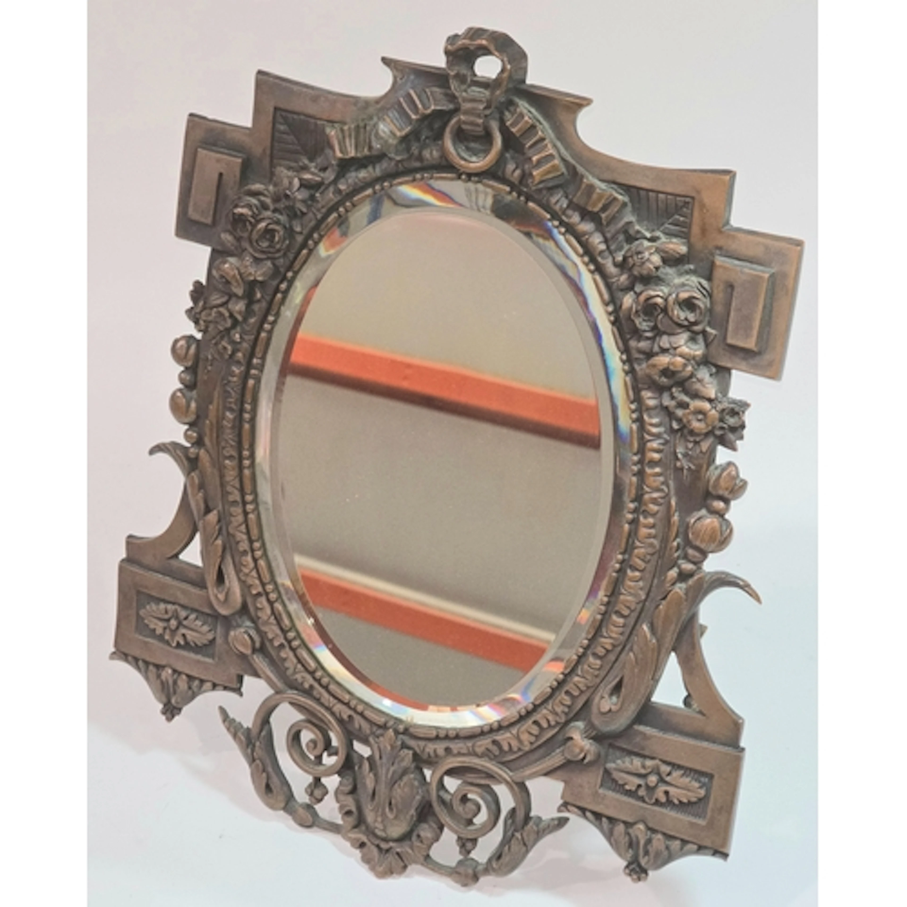 An antique bronze tabletop easel mirror featuring an oval be...
