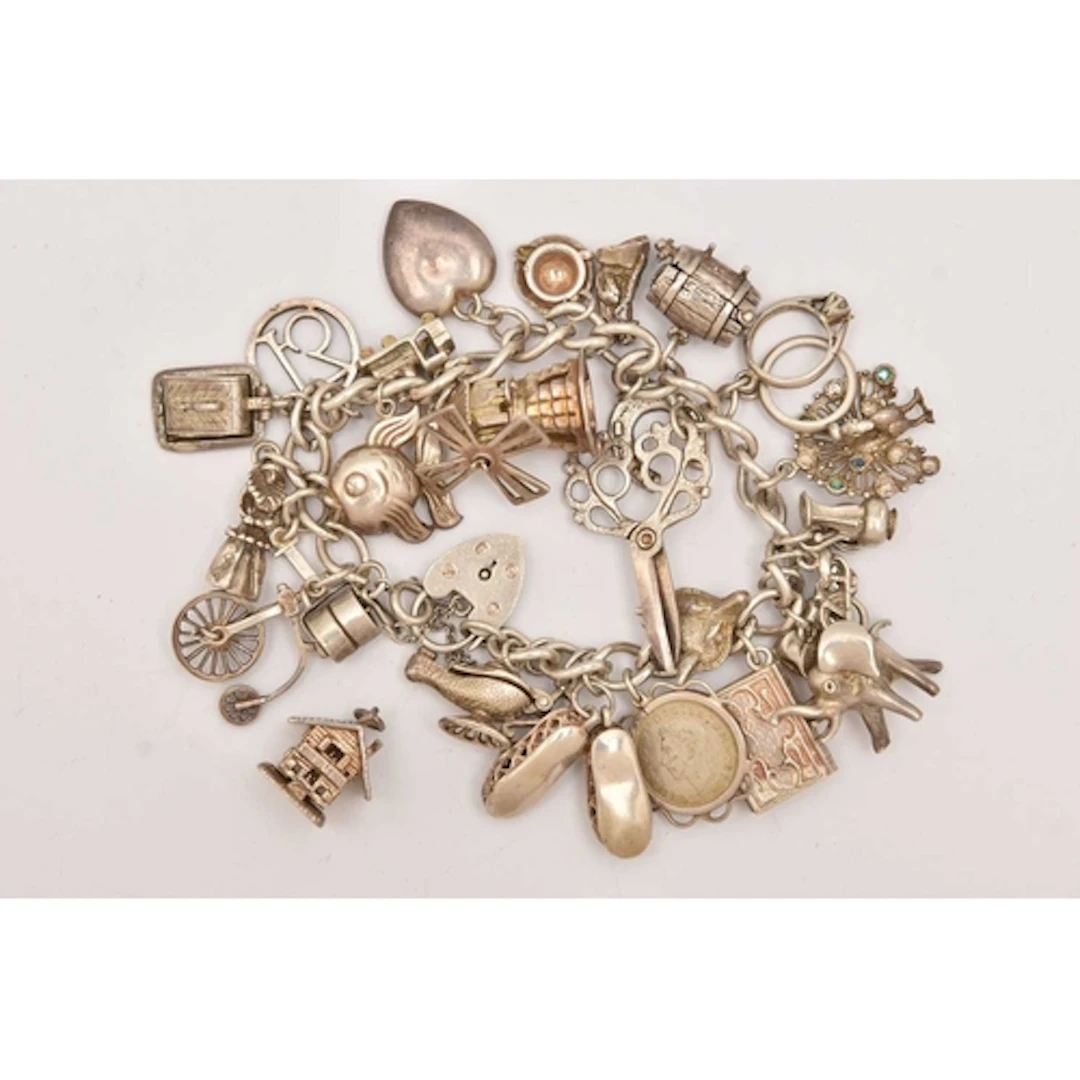 A WHITE METAL CHARM BRACELET, curb link bracelet fitted with...