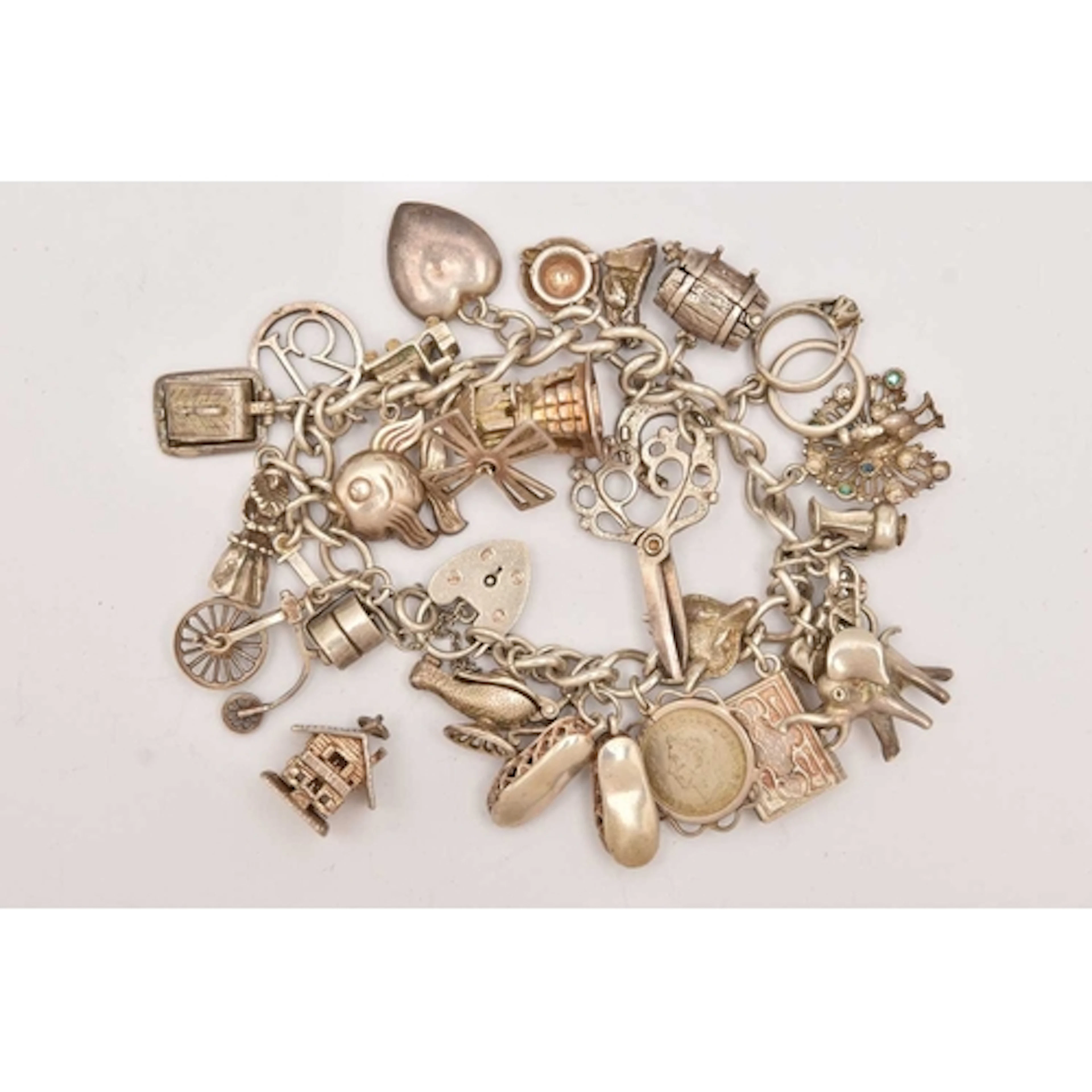 A WHITE METAL CHARM BRACELET, curb link bracelet fitted with...