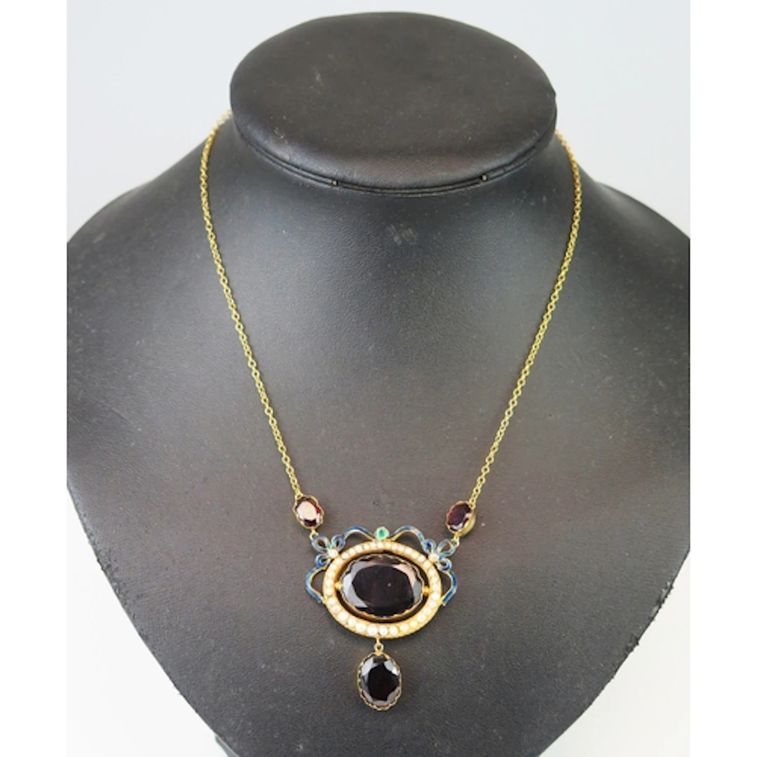A garnet, emerald, diamond and seed pearl necklace in an 18K...