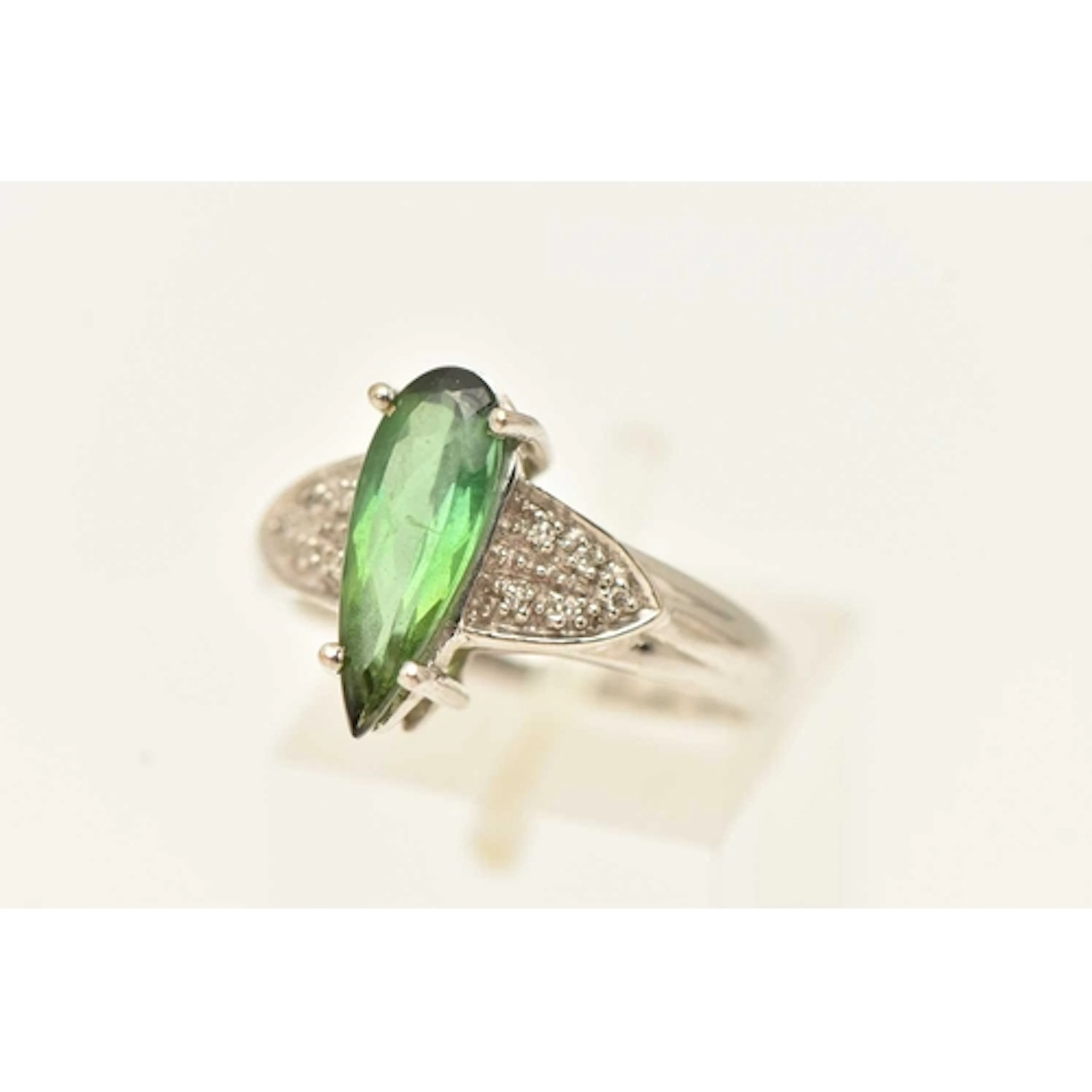 AN 18CT WHITE GOLD GEM SET RING, an elongated pear cut green...