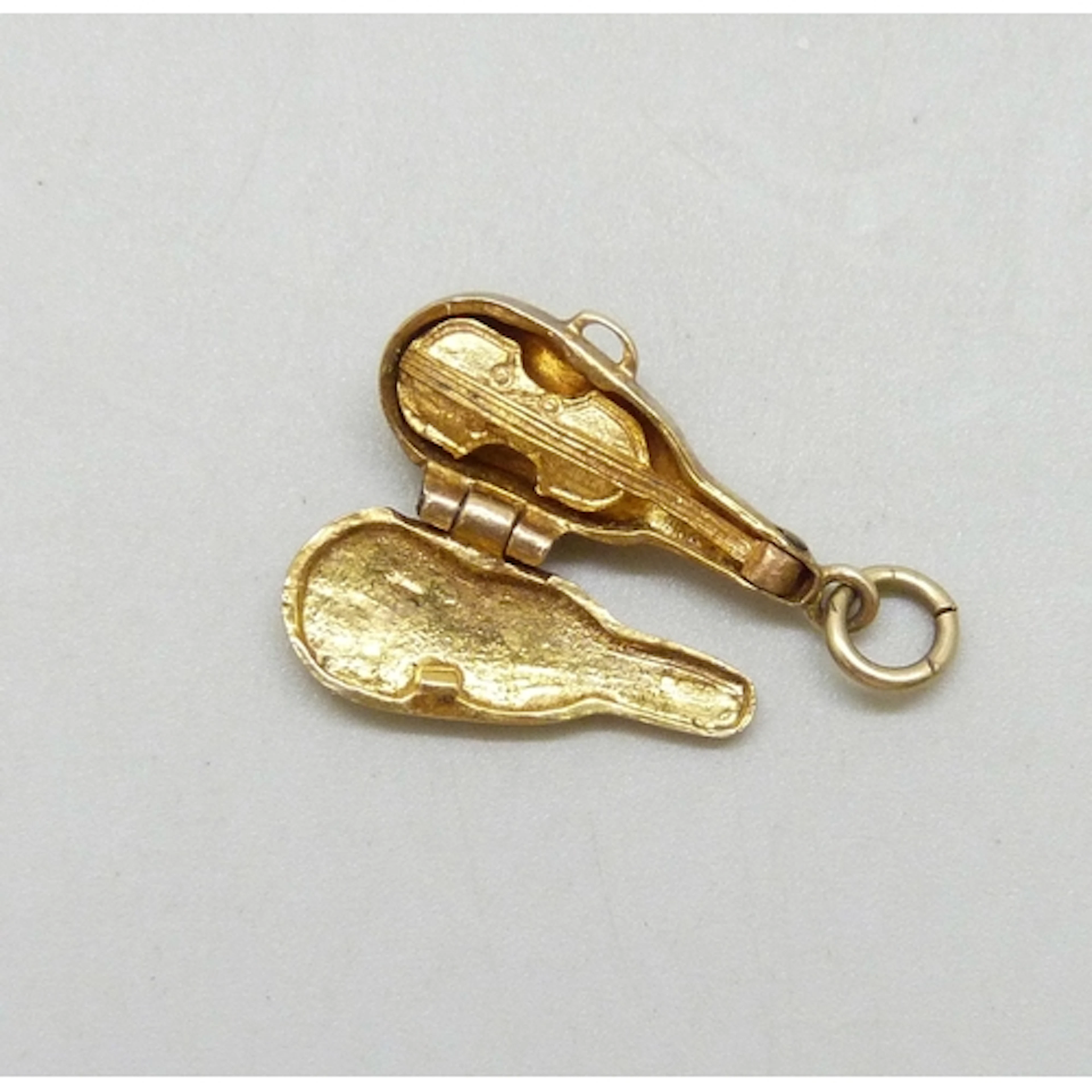A 9ct gold charm in the form of a violin in a case, the case...