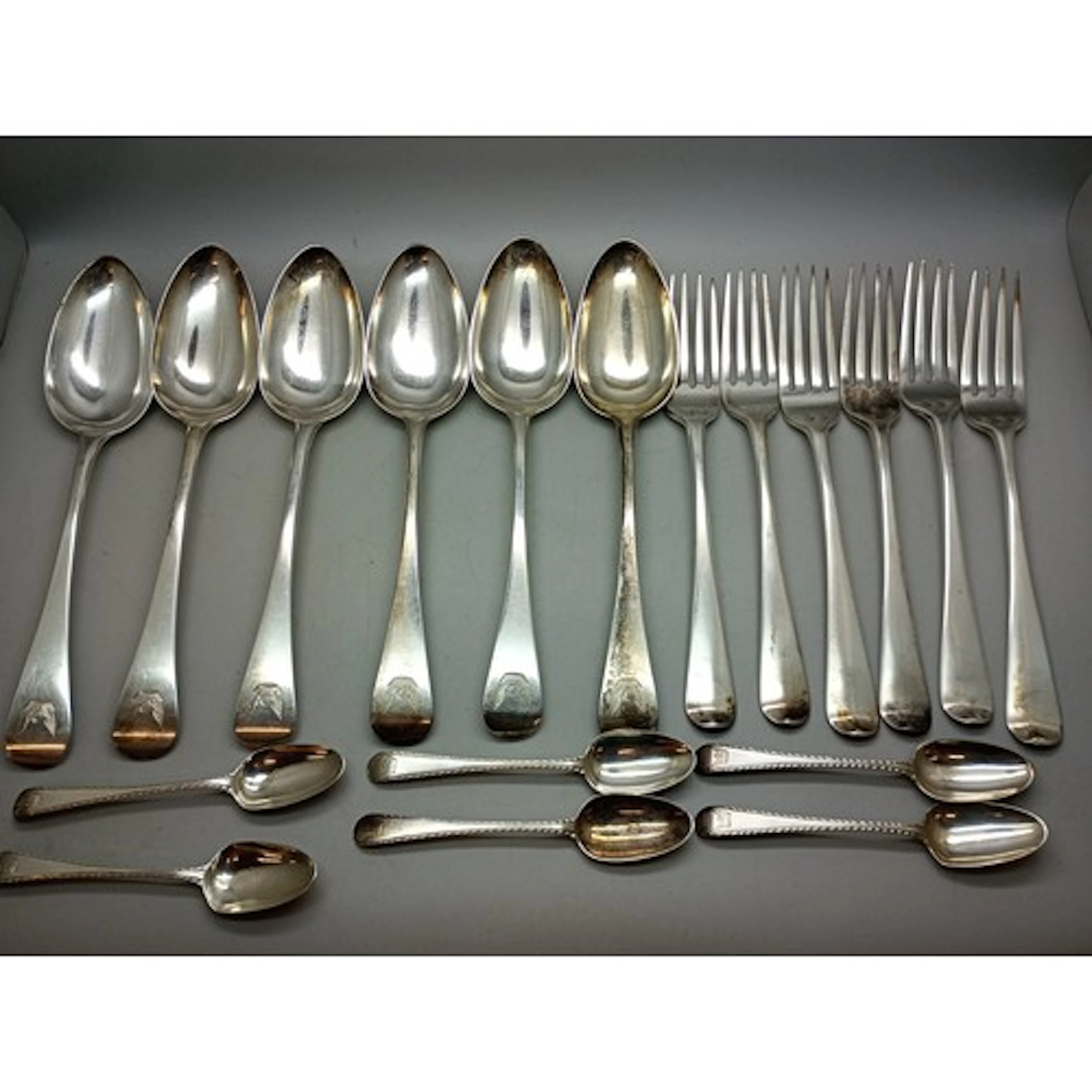 A collection of George III silver cutlery with matching cres...