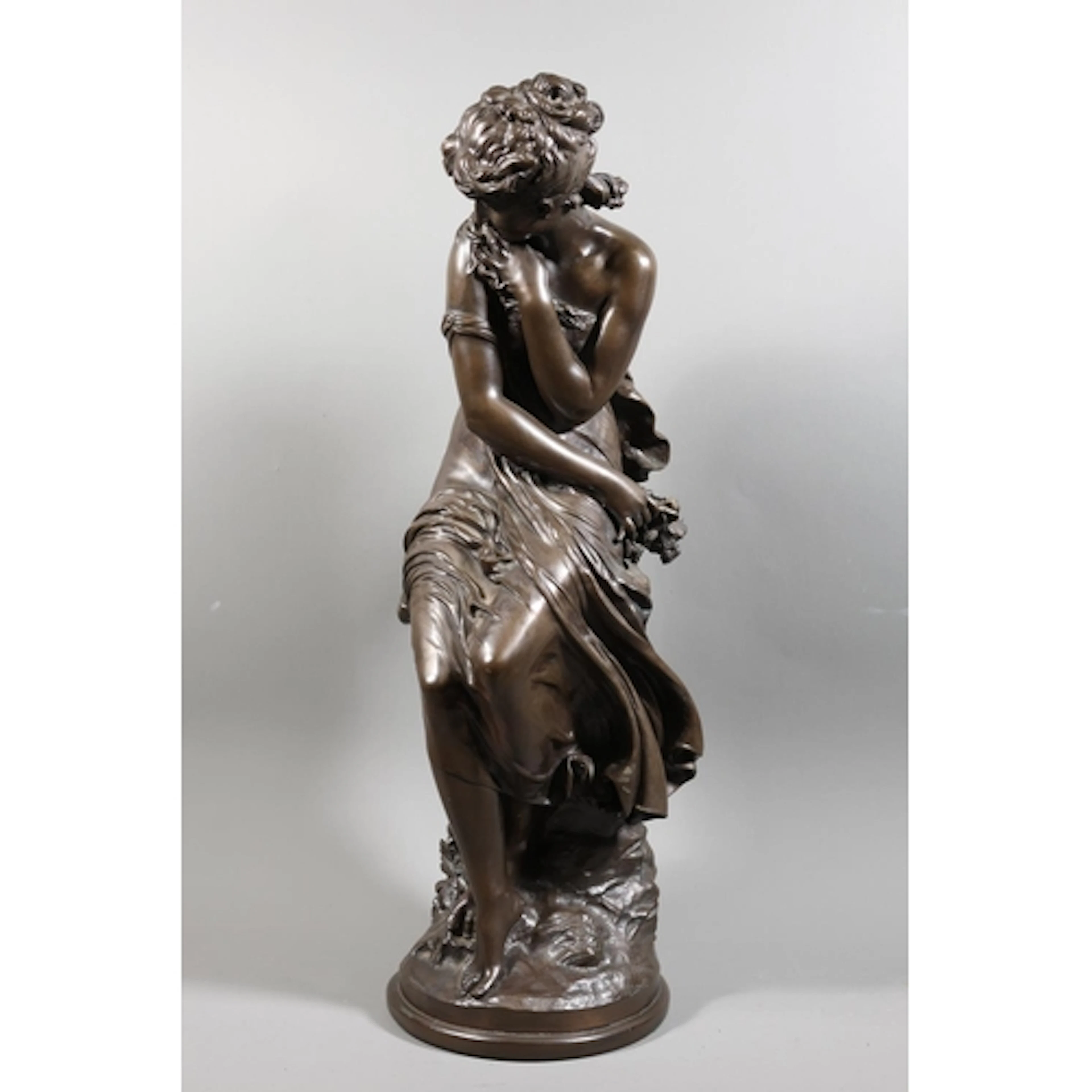 Bronzed figure of a seated young lady of a classical form ho...