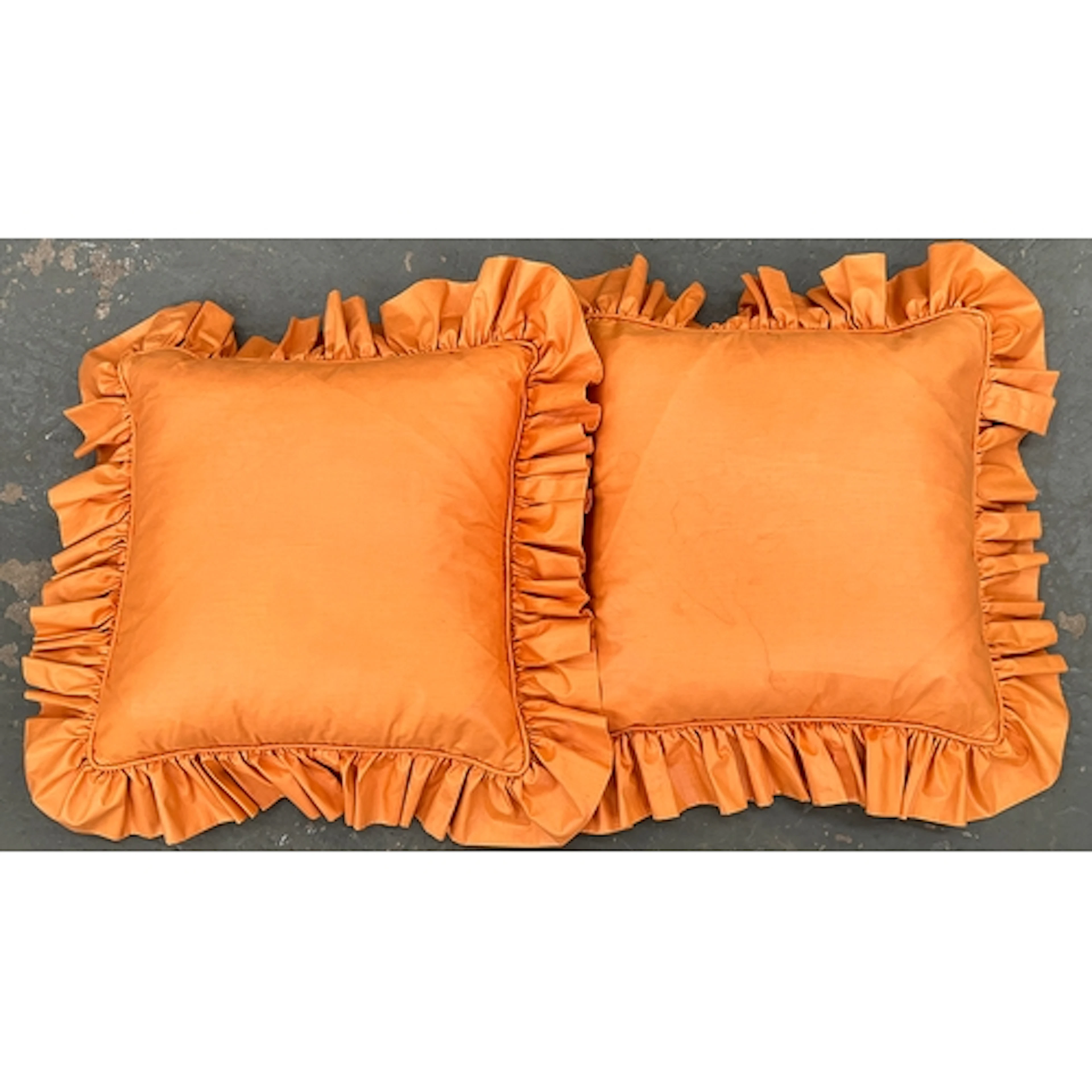 A pair of orange chintz frilled feather filled cushions, 40c...