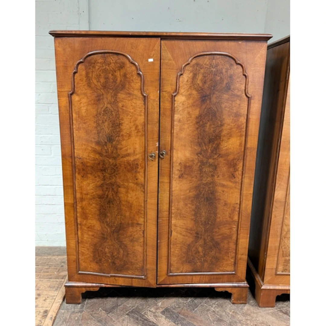 A burr walnut panelled two door wardrobe, standing on bracke...