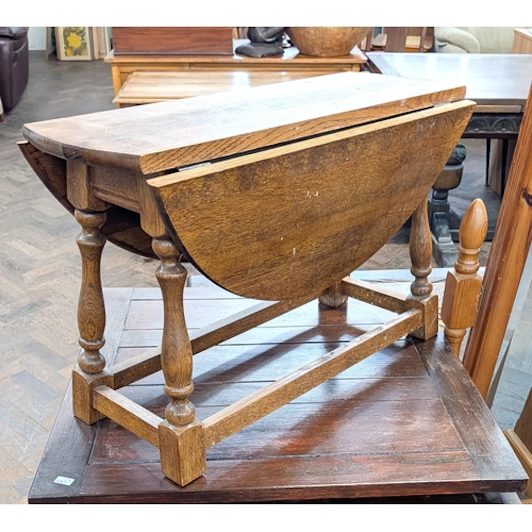 A small circular oak drop leaf coffee table on turned legs