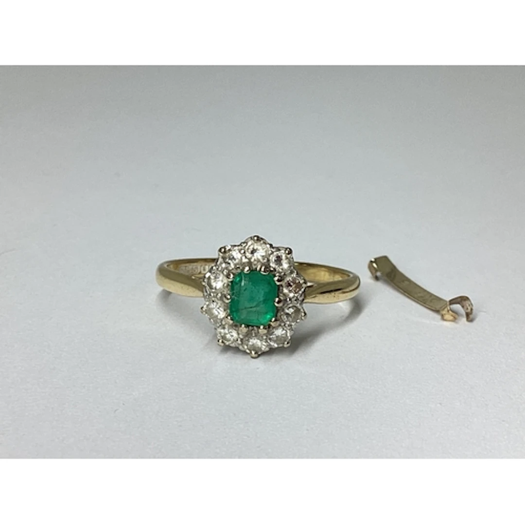 An 18ct Gold Emerald and Diamond Cluster Ring, claw set to t...