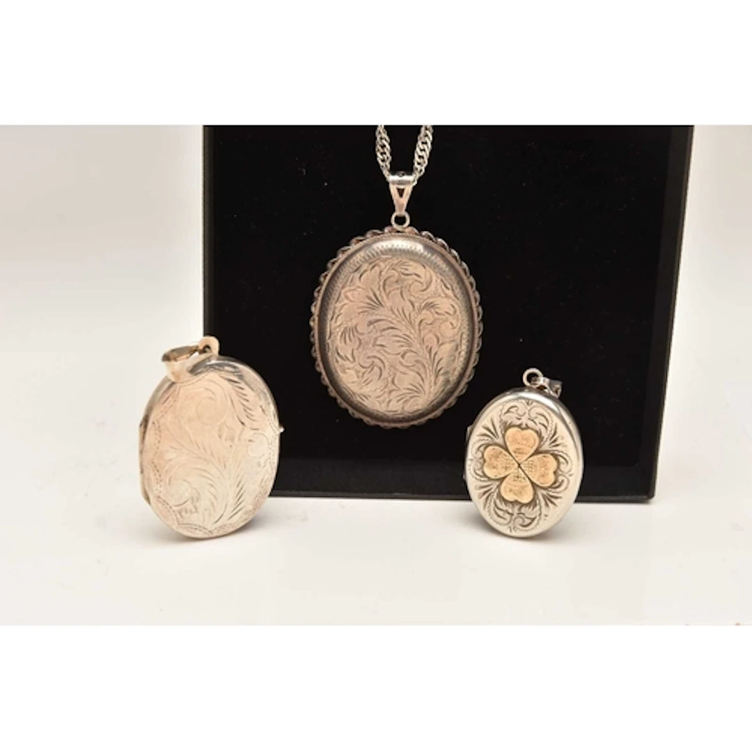 THREE SILVER OVAL PENDANT LOCKETS AND A CHAIN, the larger lo...