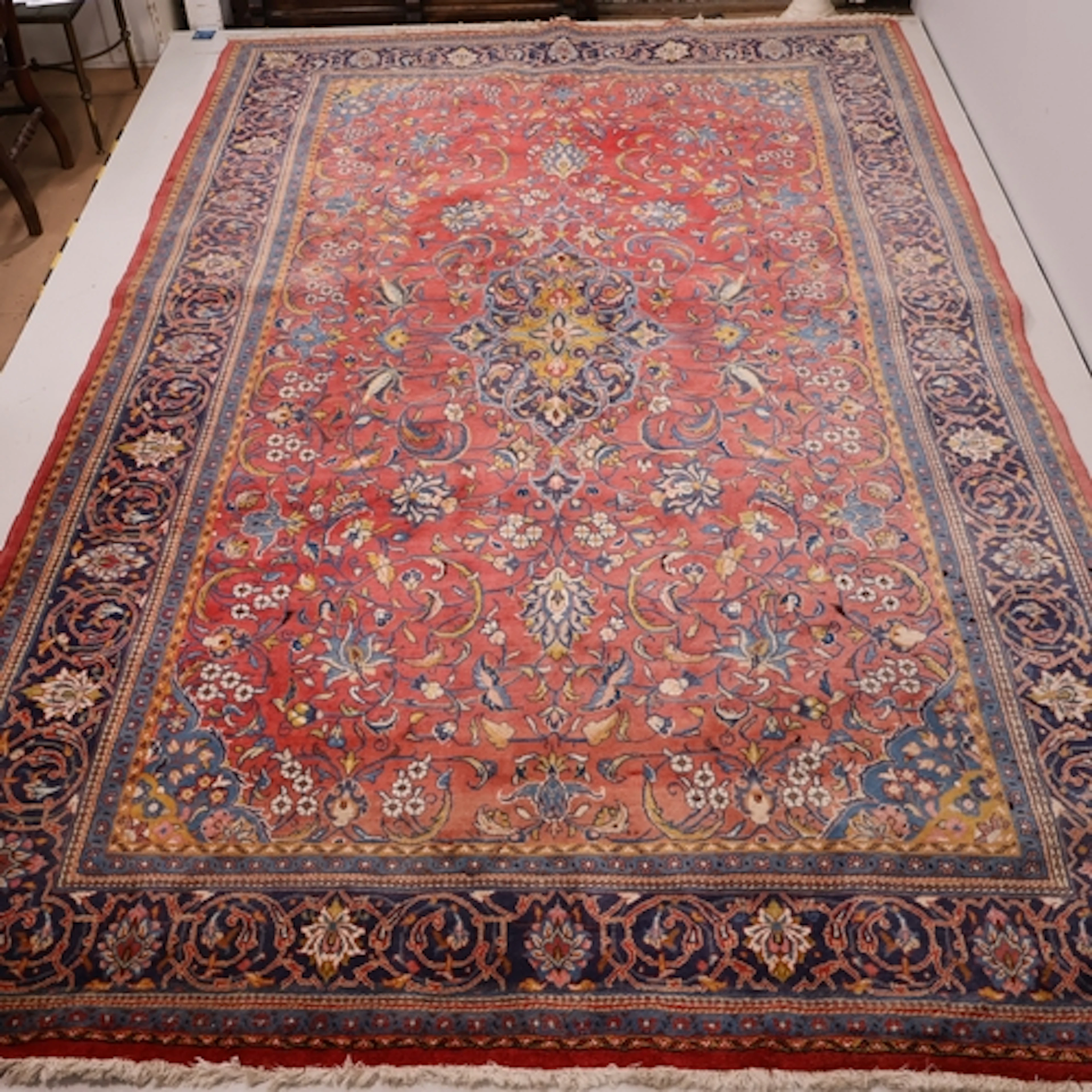 A large red ground Persian Mashad carpet, L347cm, W215cm.