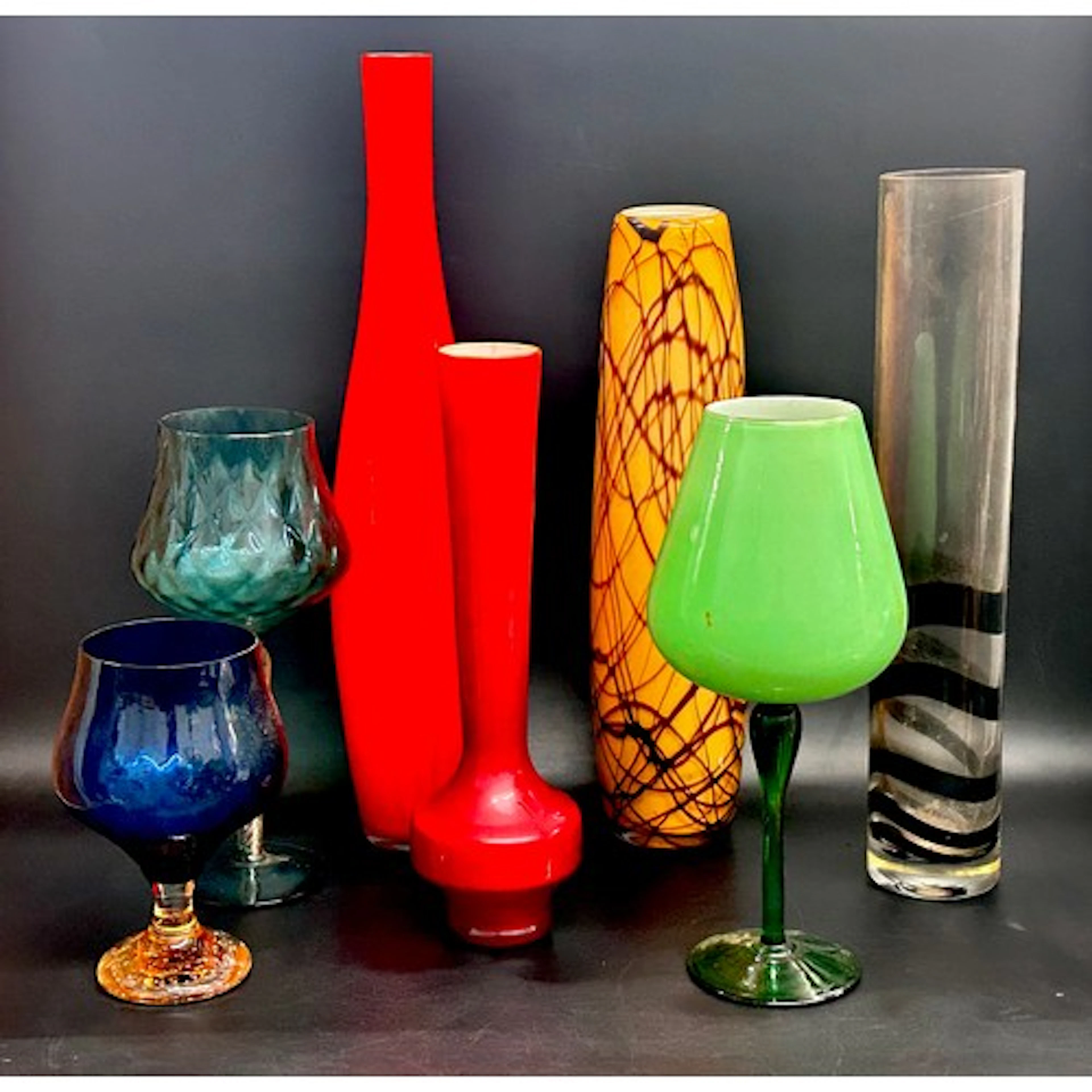 A collection of oversized coloured wine / brandy glasses, wi...