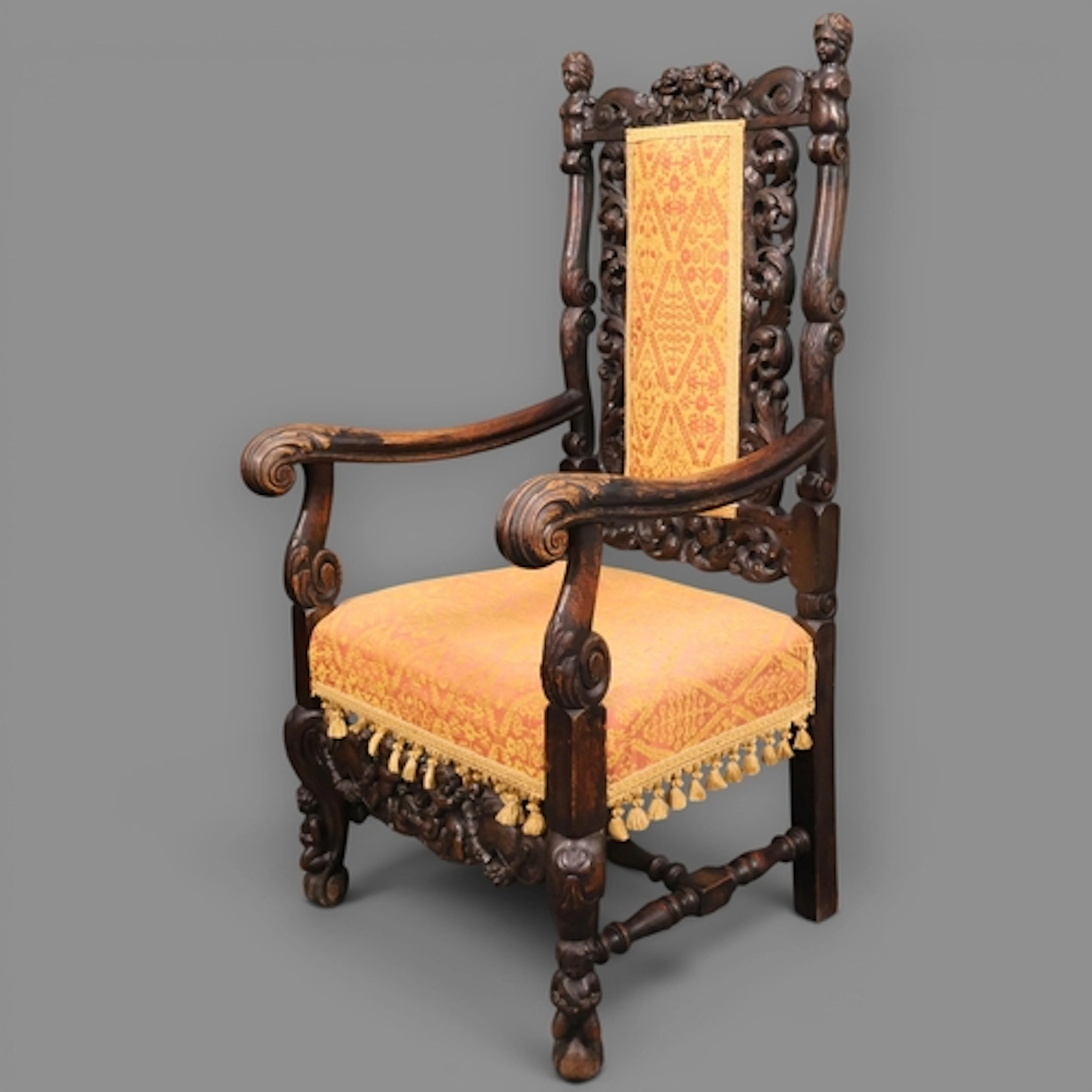 An antique oak and upholstered Carolean style open arm chair...