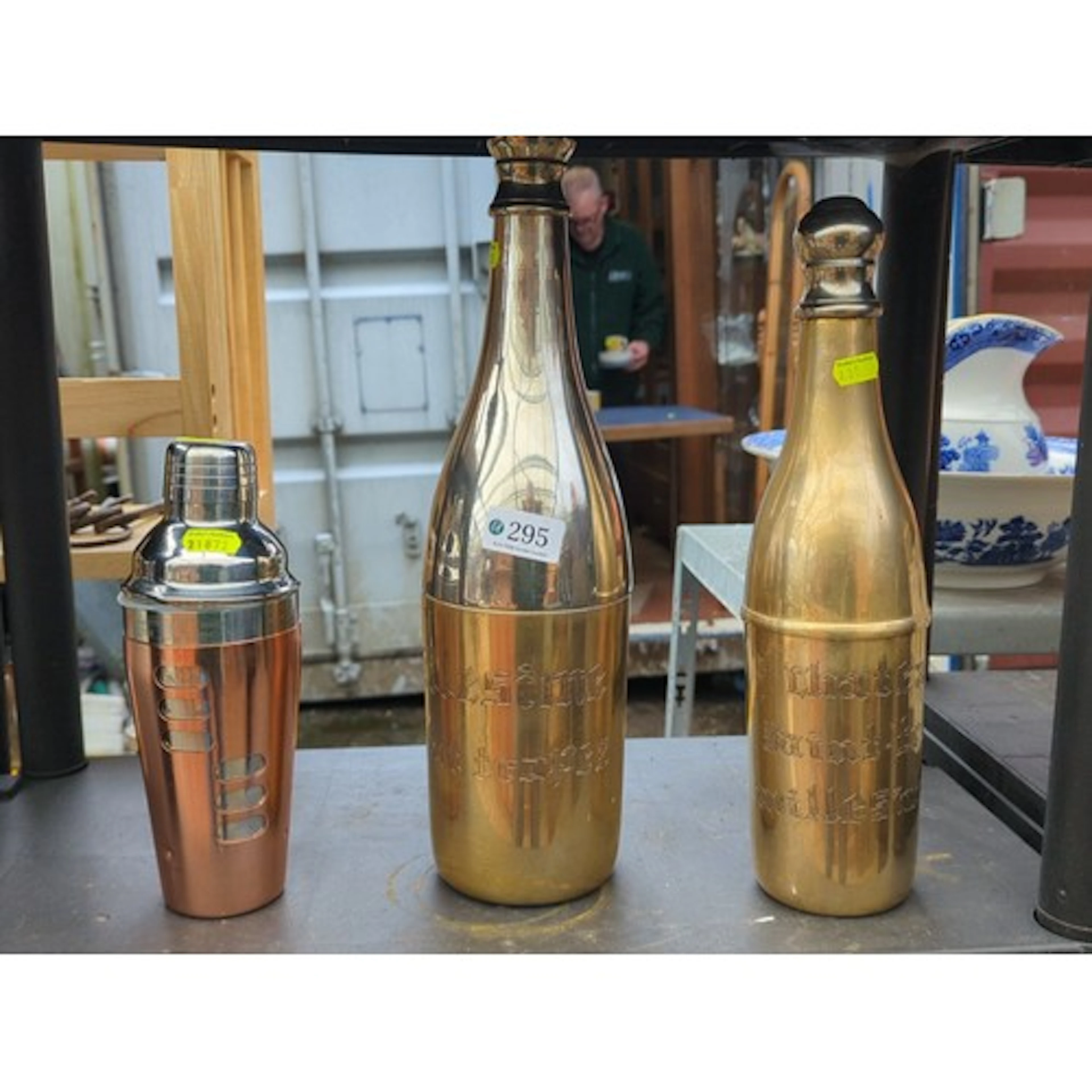 Brass bottle-form champagne coolers, engraved in Gothic scri...