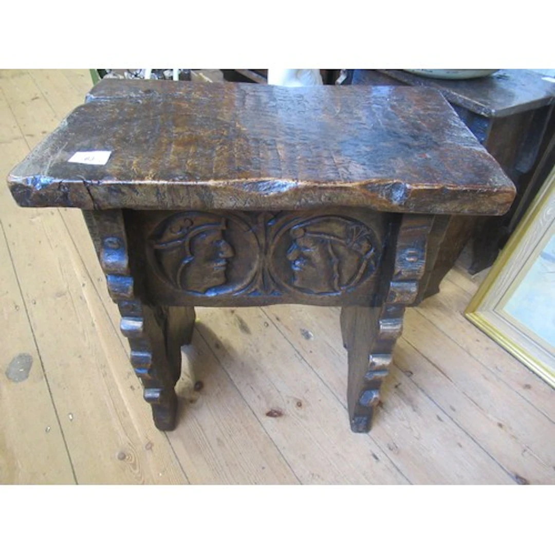 An antique style oak joint stool each side carved with faces...