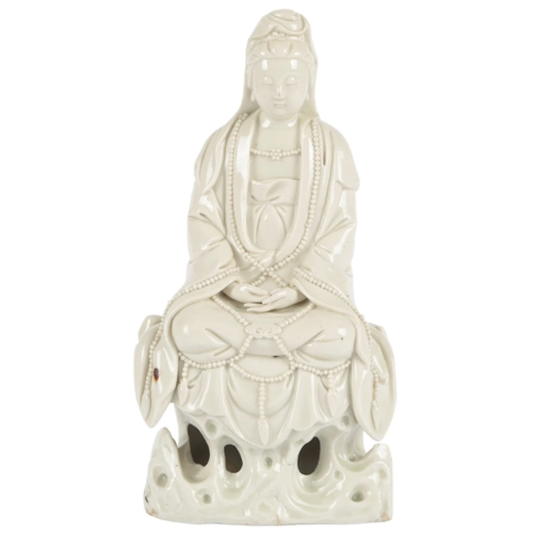 A Chinese blanc-de-chine figure of Guanyin, seated on a rock...