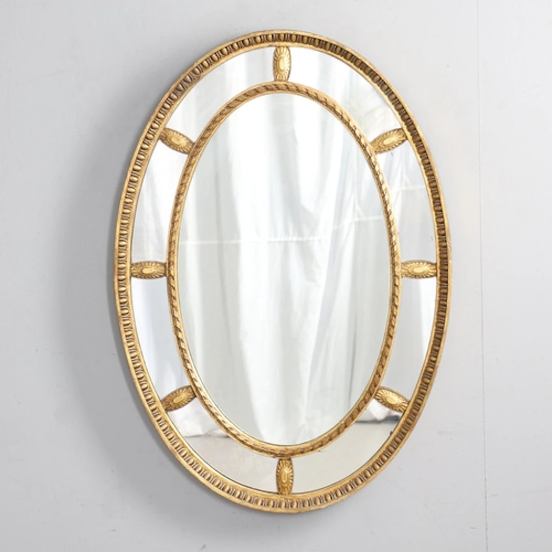 AN ADAMS STYLE GILT GESSO OVAL WALL MIRROR. early 20th centu...