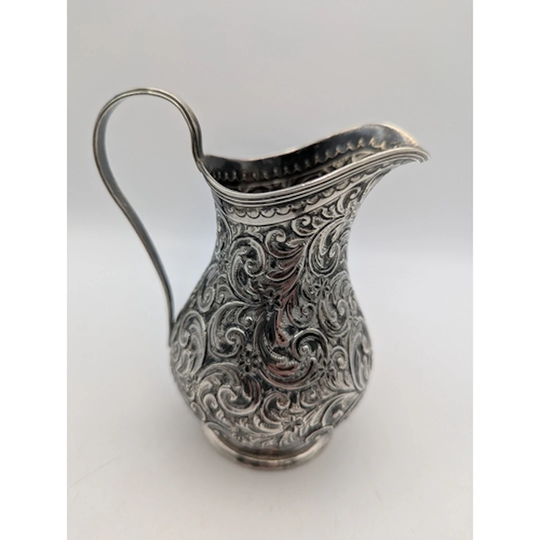 A late Victorian silver jug decorated with an engraved scrol...