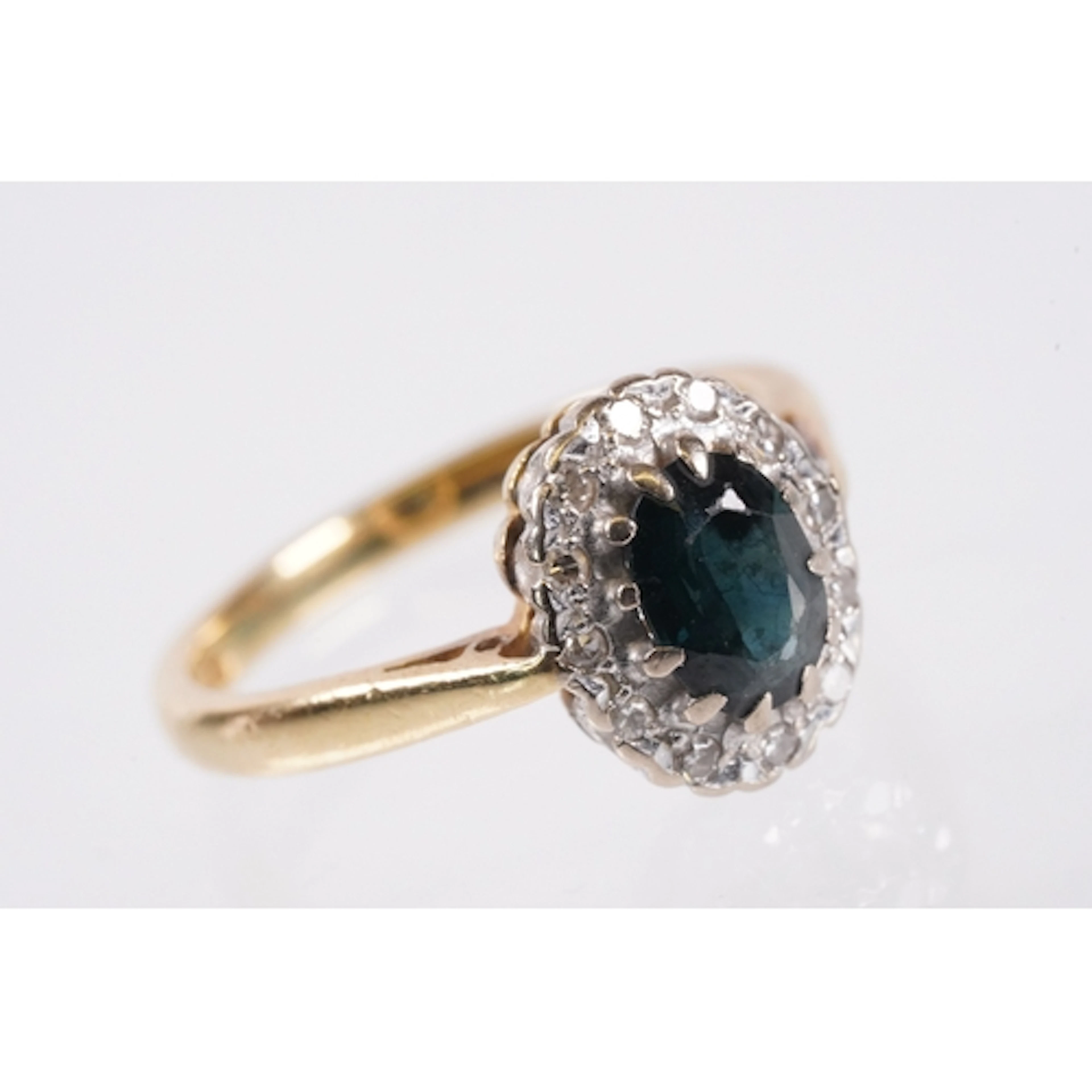 18ct gold, sapphire and diamond halo ring. The ring having a...