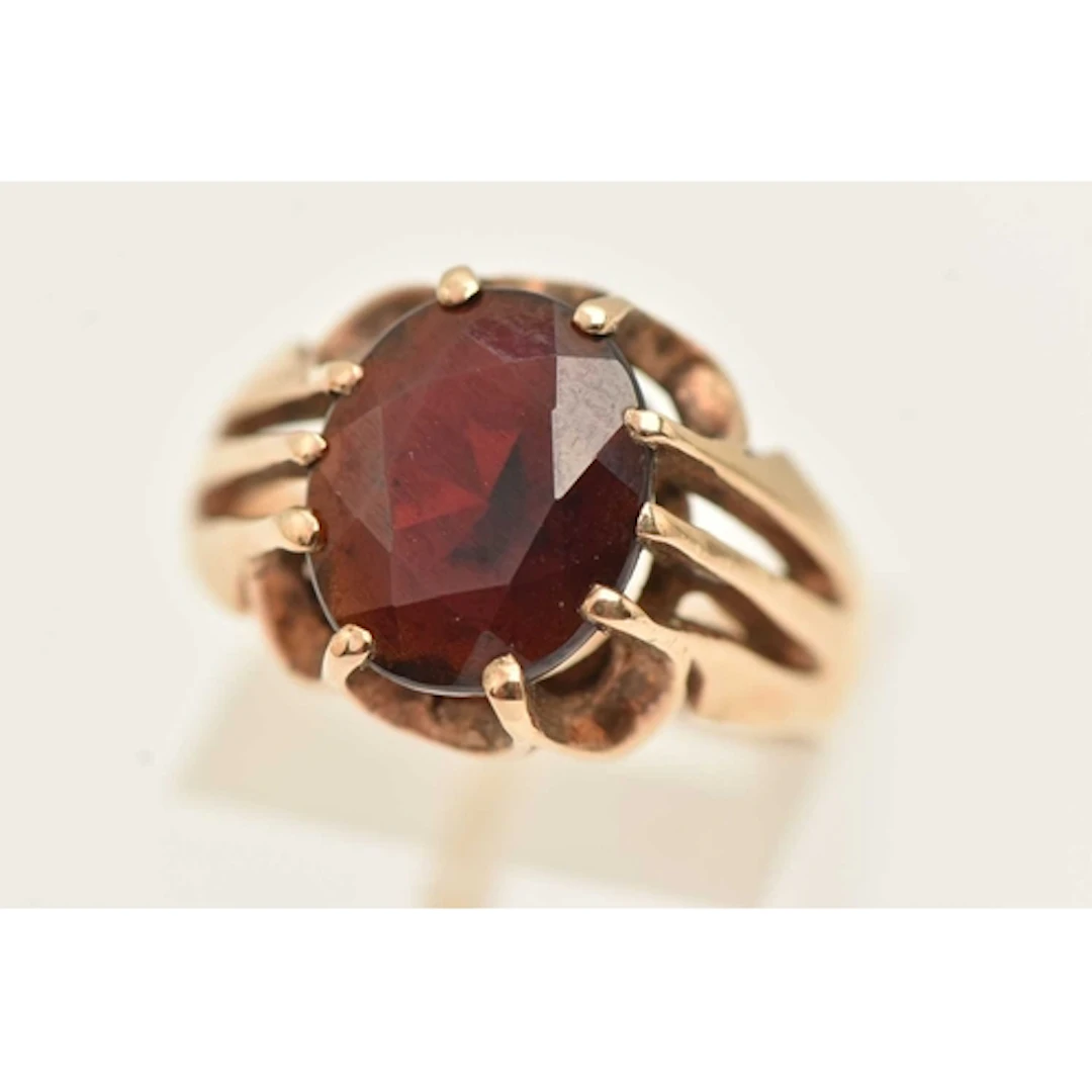 A 9CT YELLOW GOLD GEM SET RING, an oval cut garnet in a ten ...