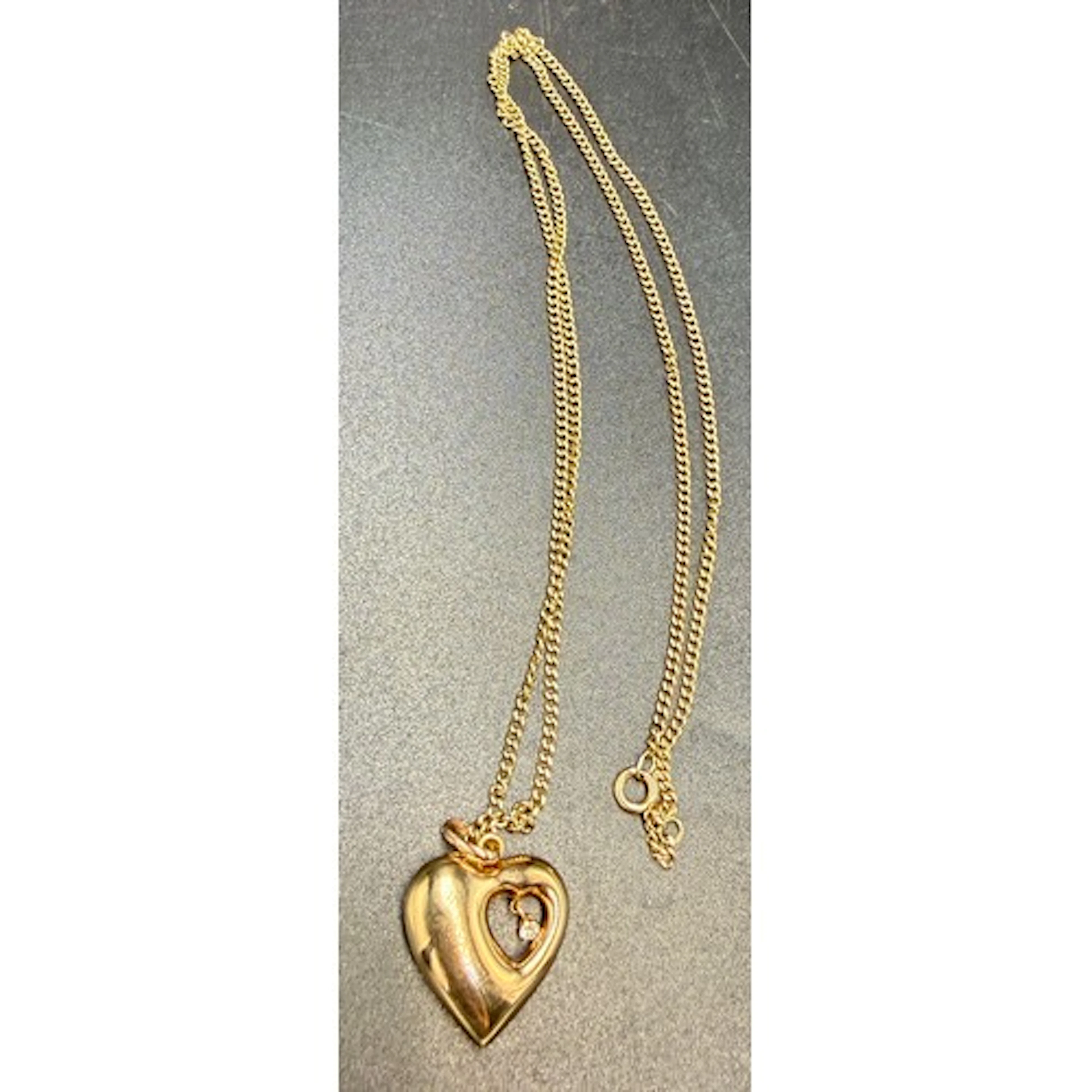 A 9 carat gold heart pendant set with single clear stone sus...