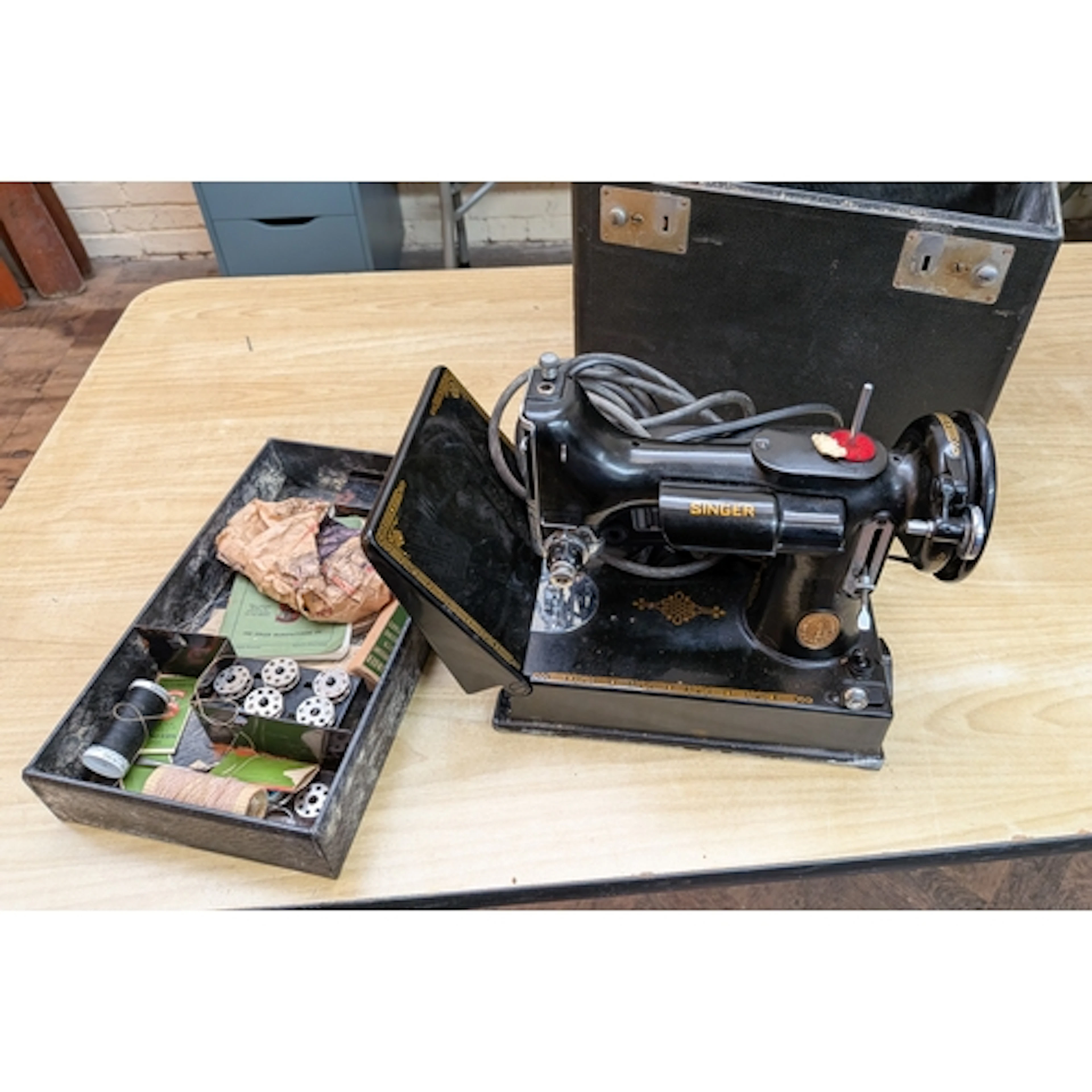 A small vintage Singer sewing machine with accessories in fi...