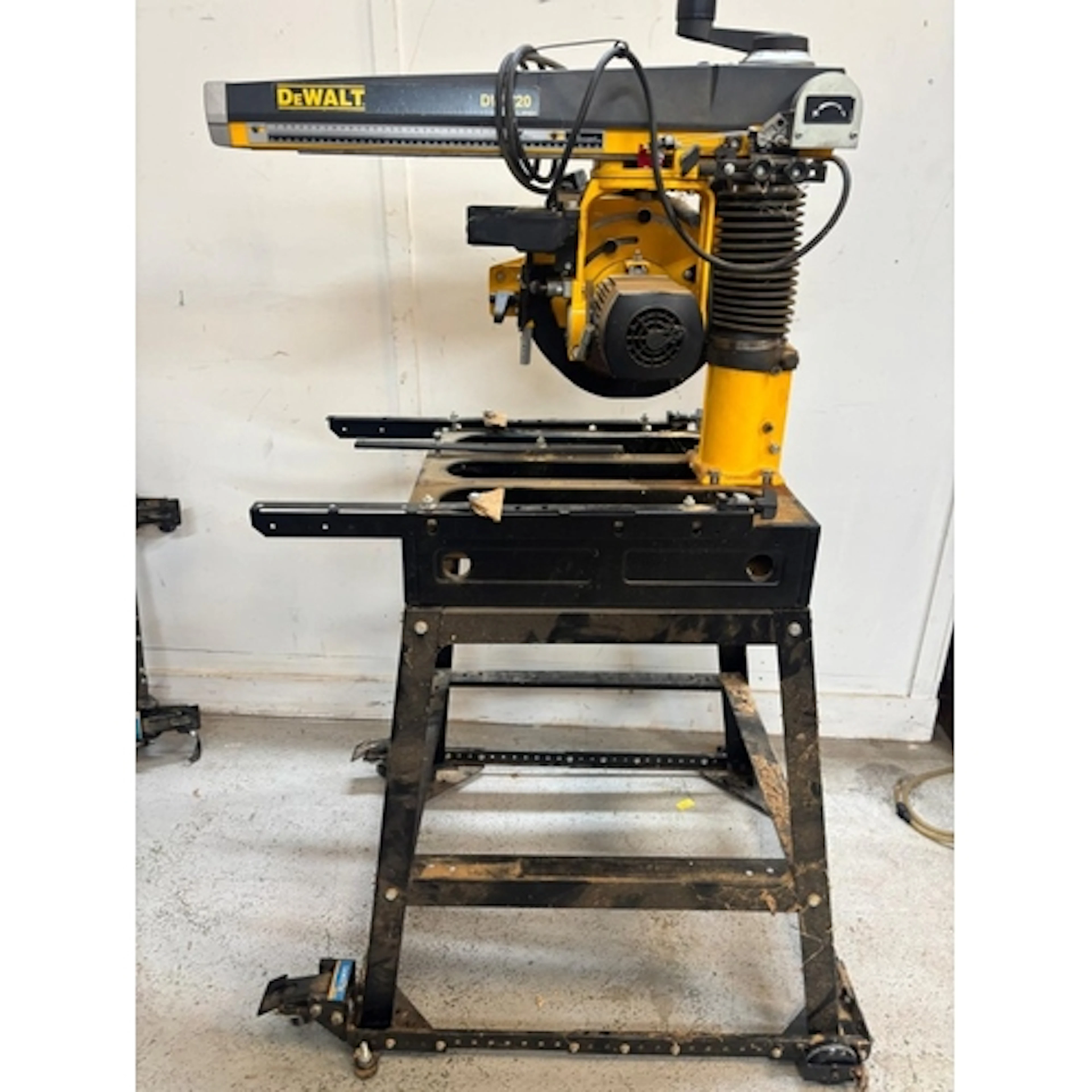 A Dewalt radial arm saw mounted on a heavy duty stand ...
