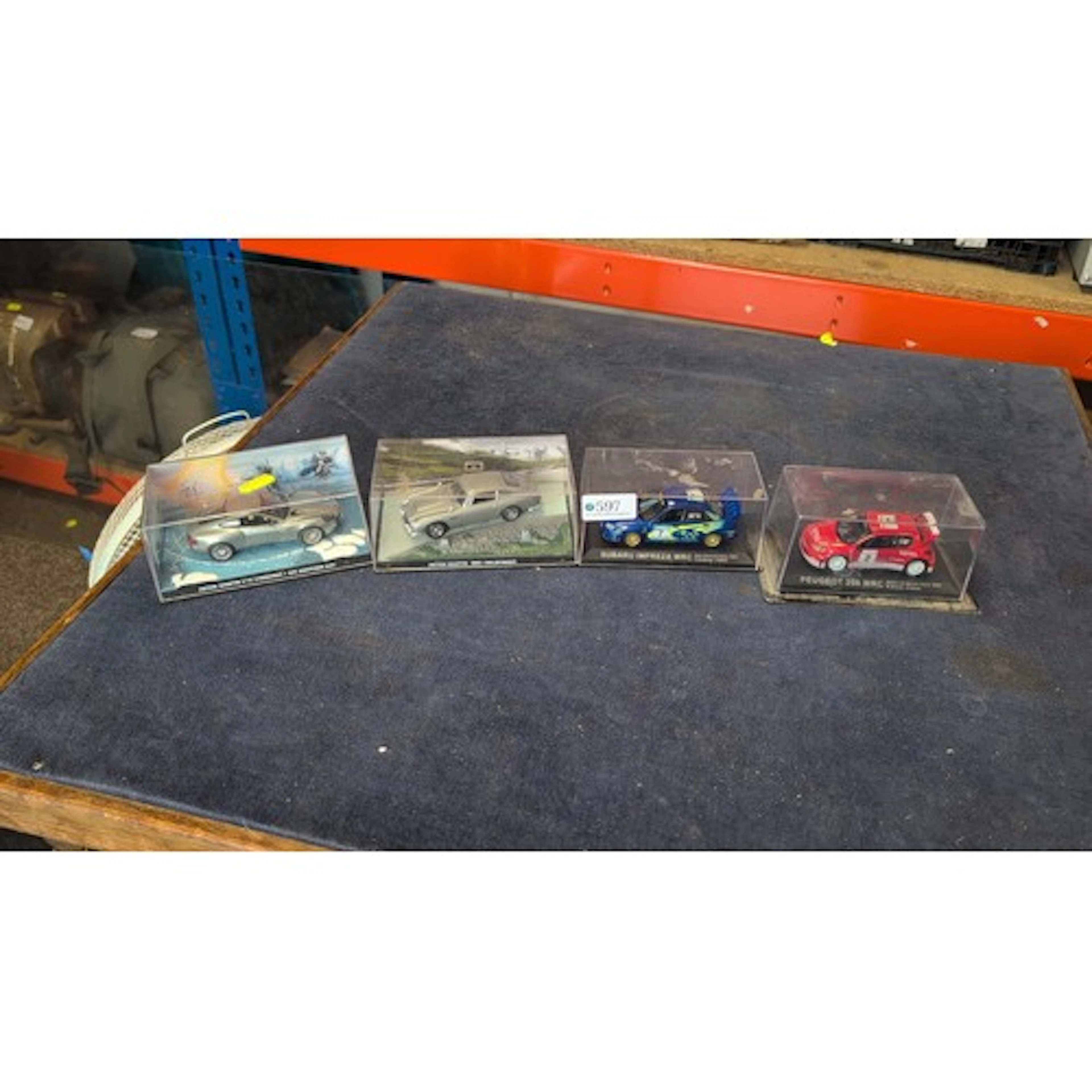 A group of four boxed die-cast model cars on display plinths...