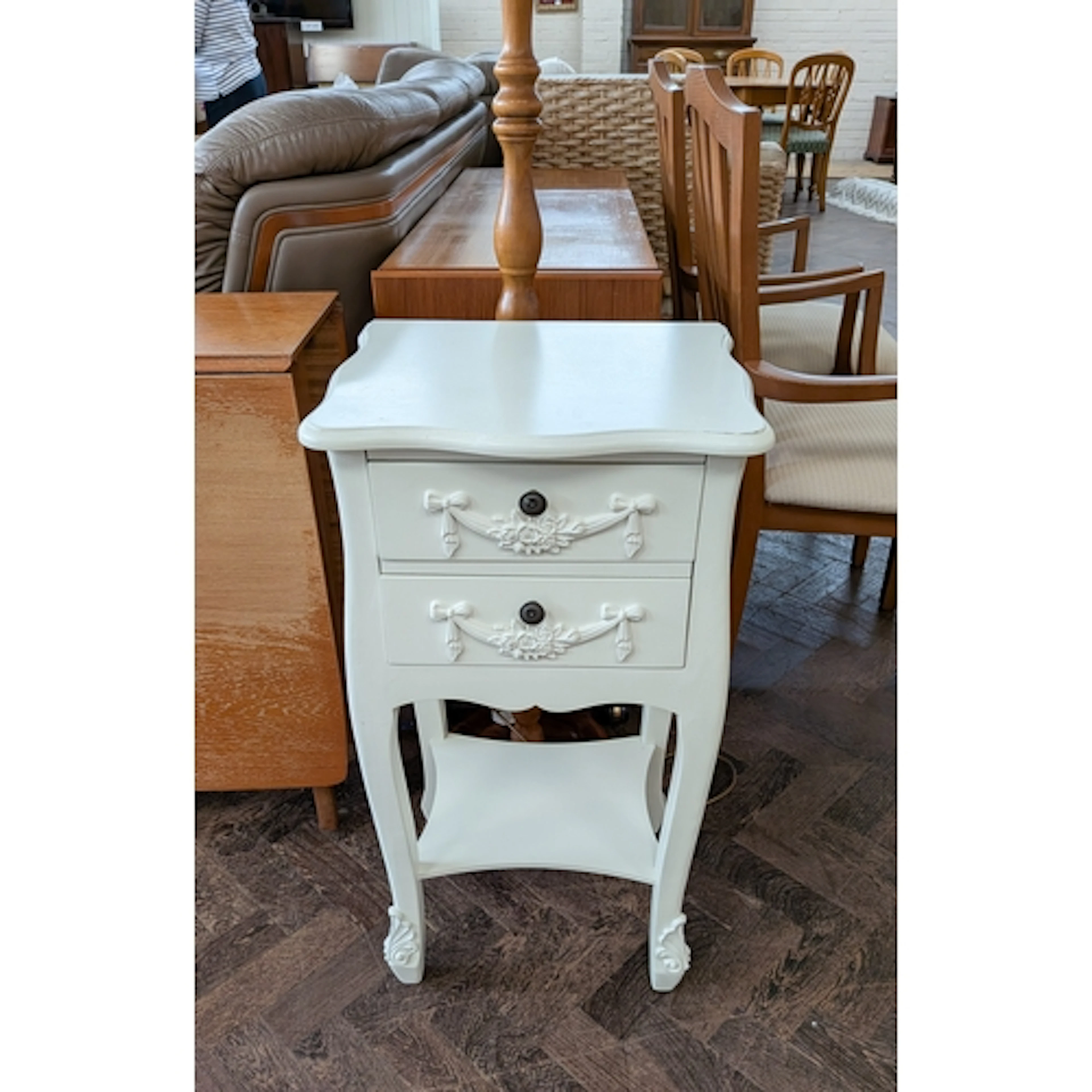 A modern standard lamp with shade and a white two drawer bed...