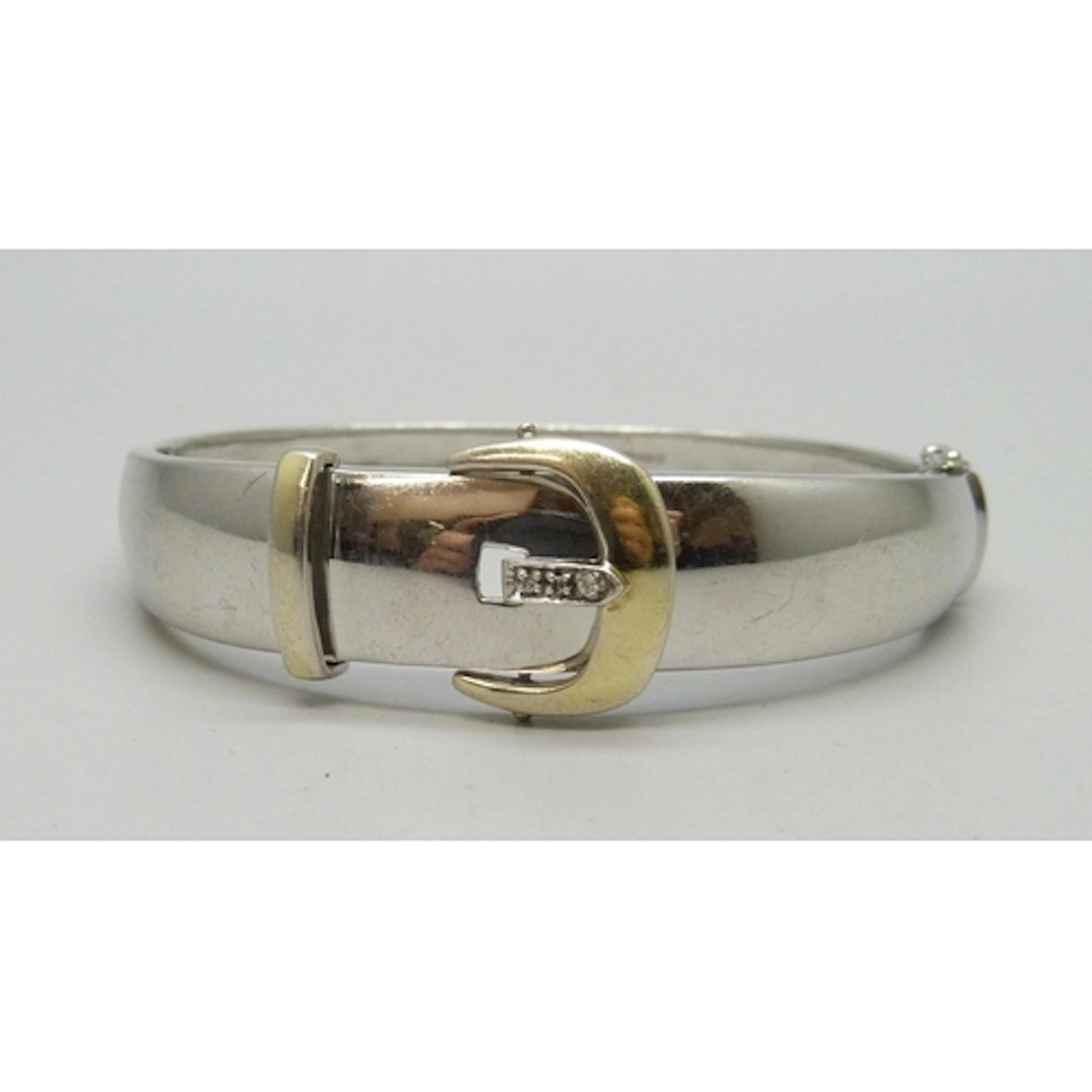 A silver buckle style bangle set with a white stone, 33g, 6....