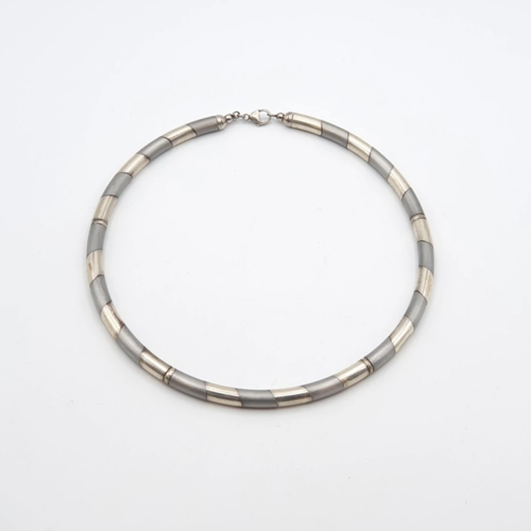 A two silver Necklace of linked tubular sections of two-tone...