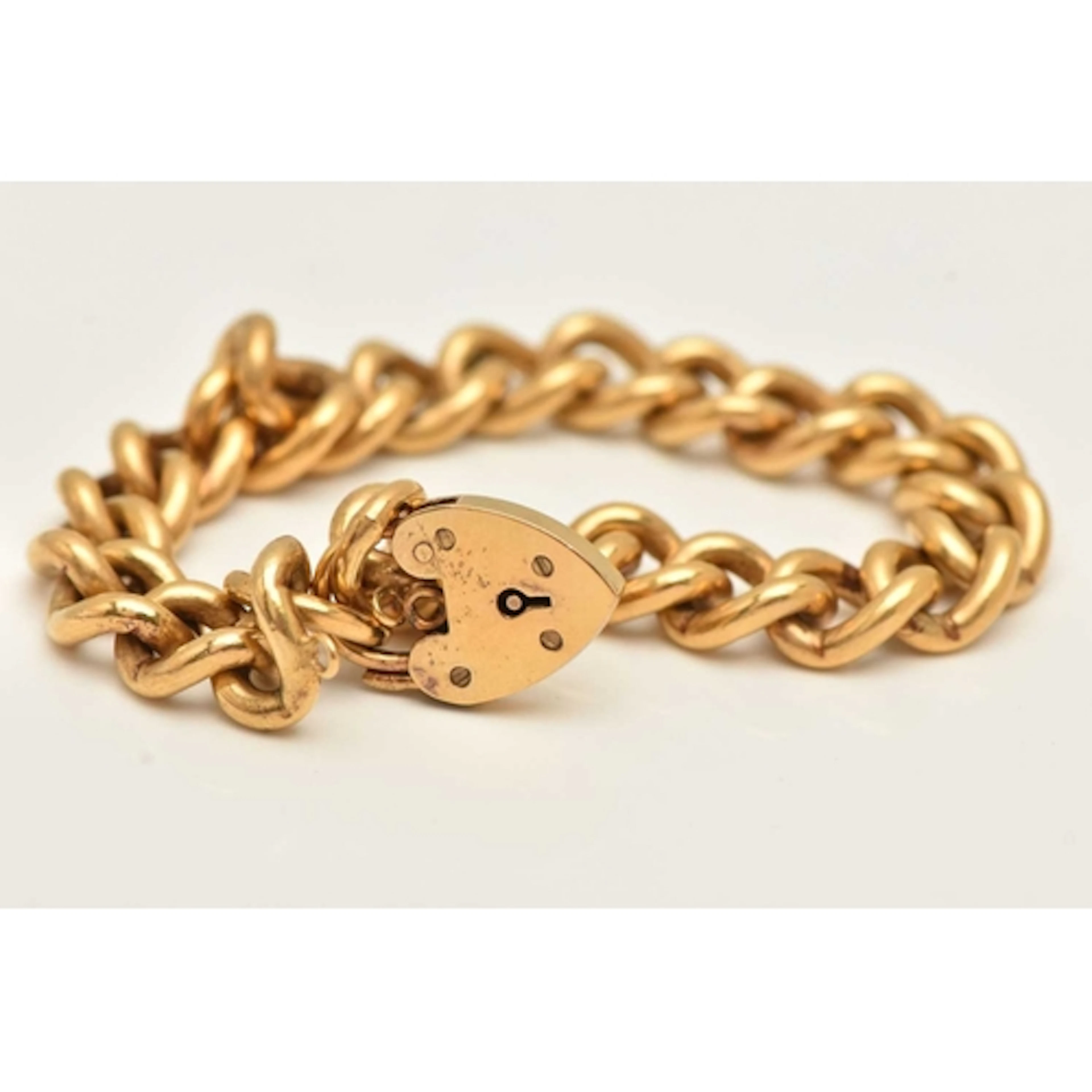 A SILVER GILT CURB LINK BRACELET, fitted with a heart padloc...