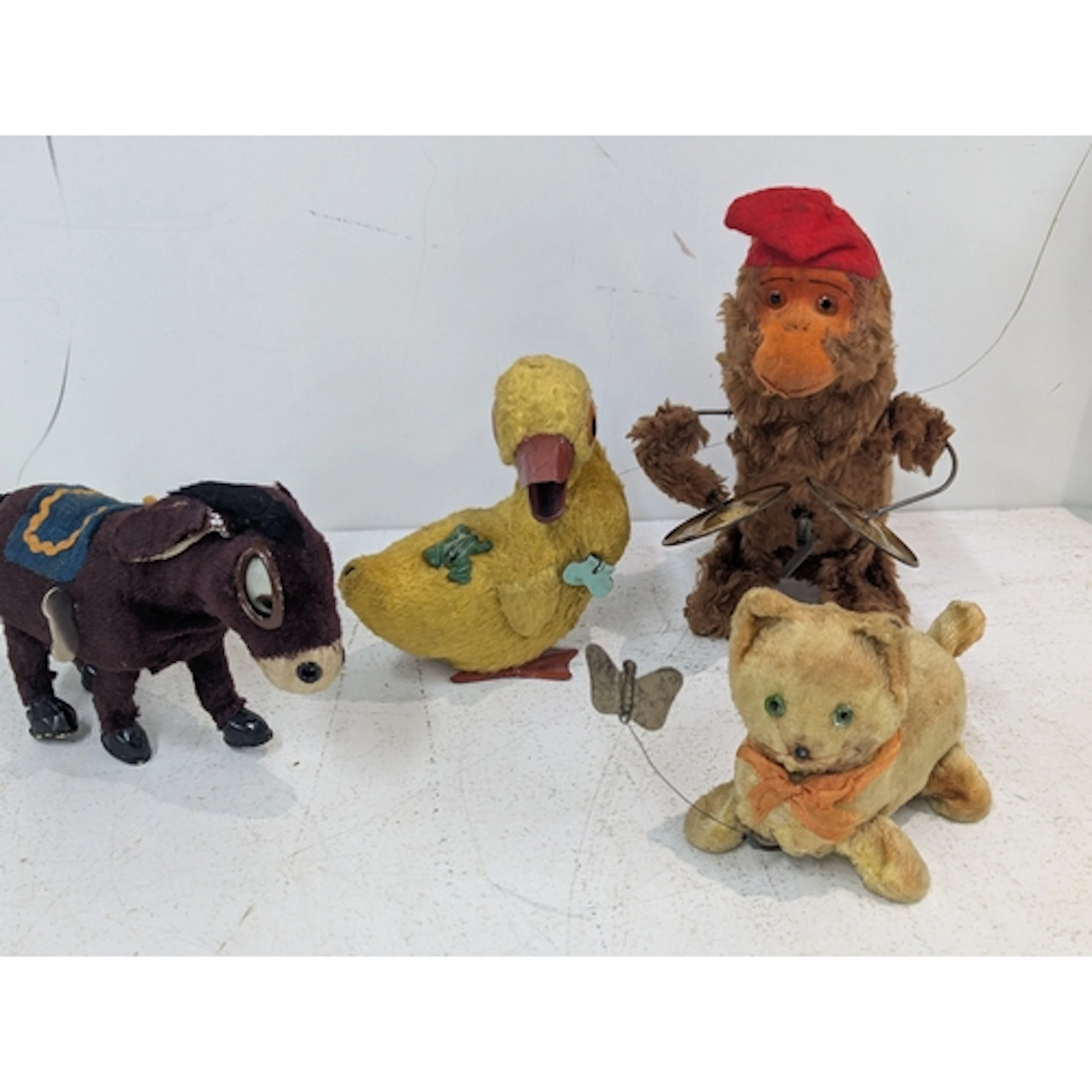Four vintage mechanical cloth and tin wind-up toys to includ...
