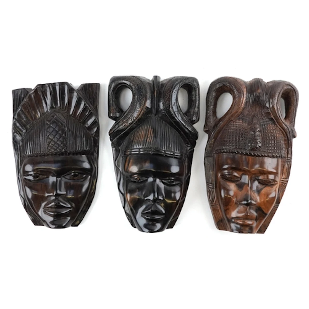 Three hand carved African hardwood wall masks, each with a c...